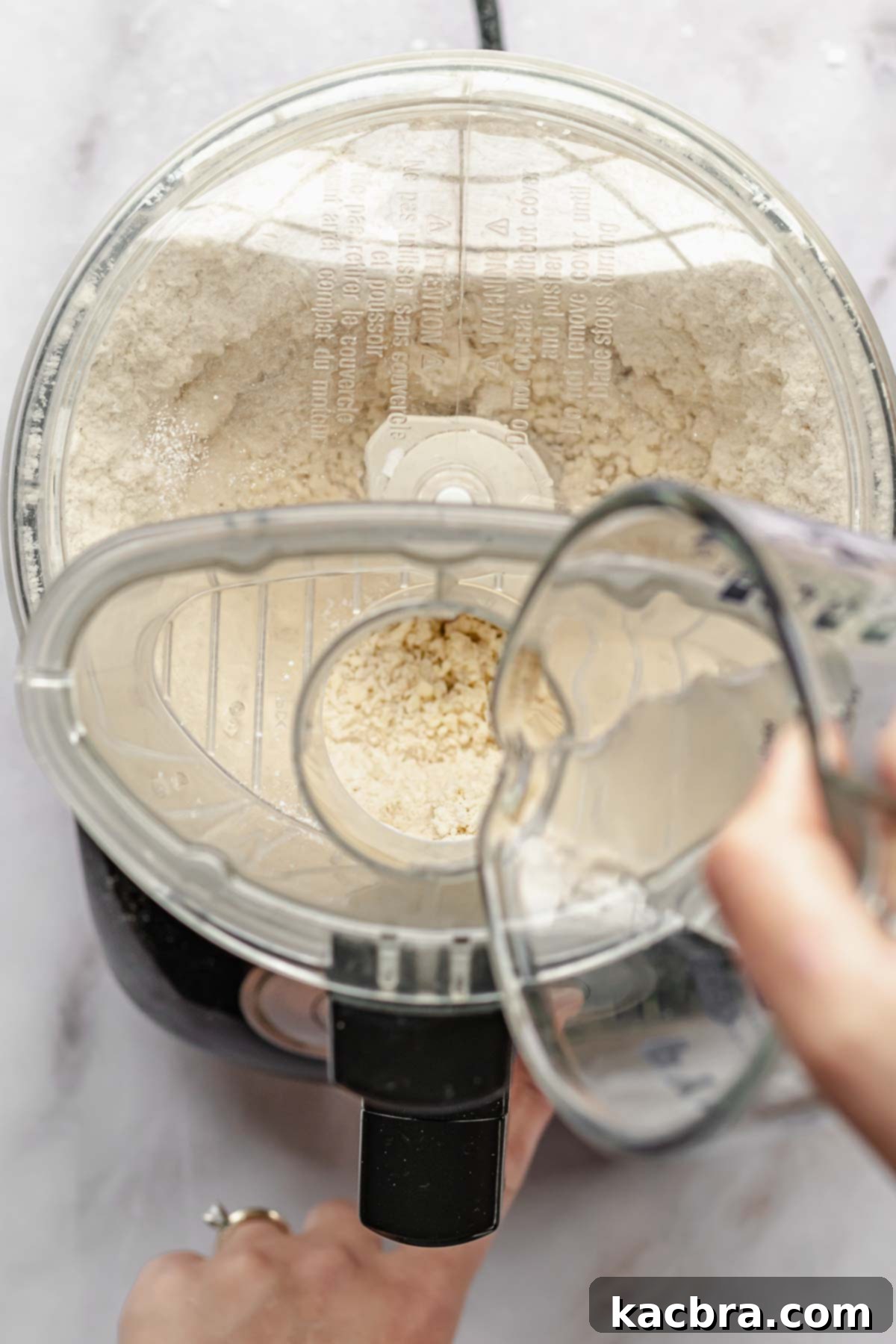 Perfectly Flaky All-Butter Crust 6 Ice water being poured through the food processor chute while pulsing.
