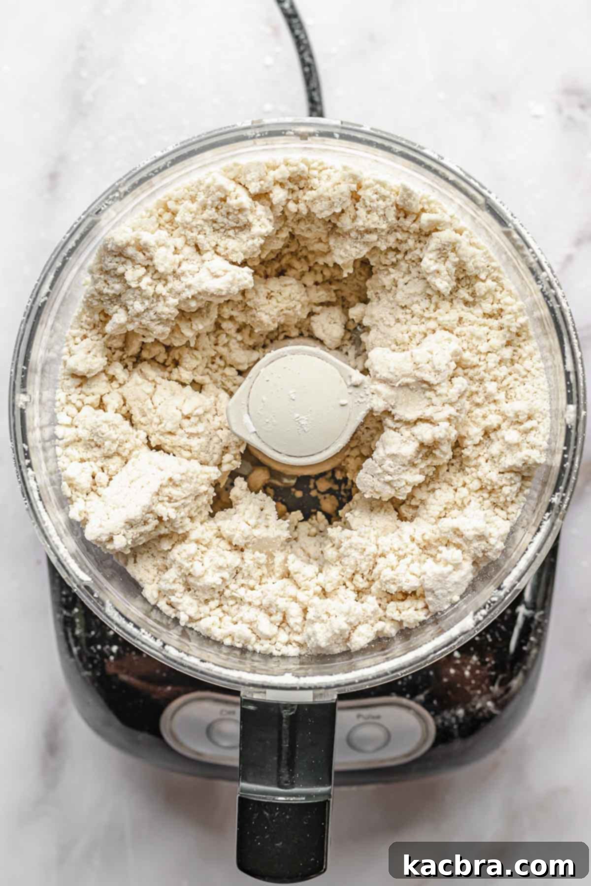 Perfectly Flaky All-Butter Crust 7 Crumbly pie dough forming in a food processor, not yet a ball.