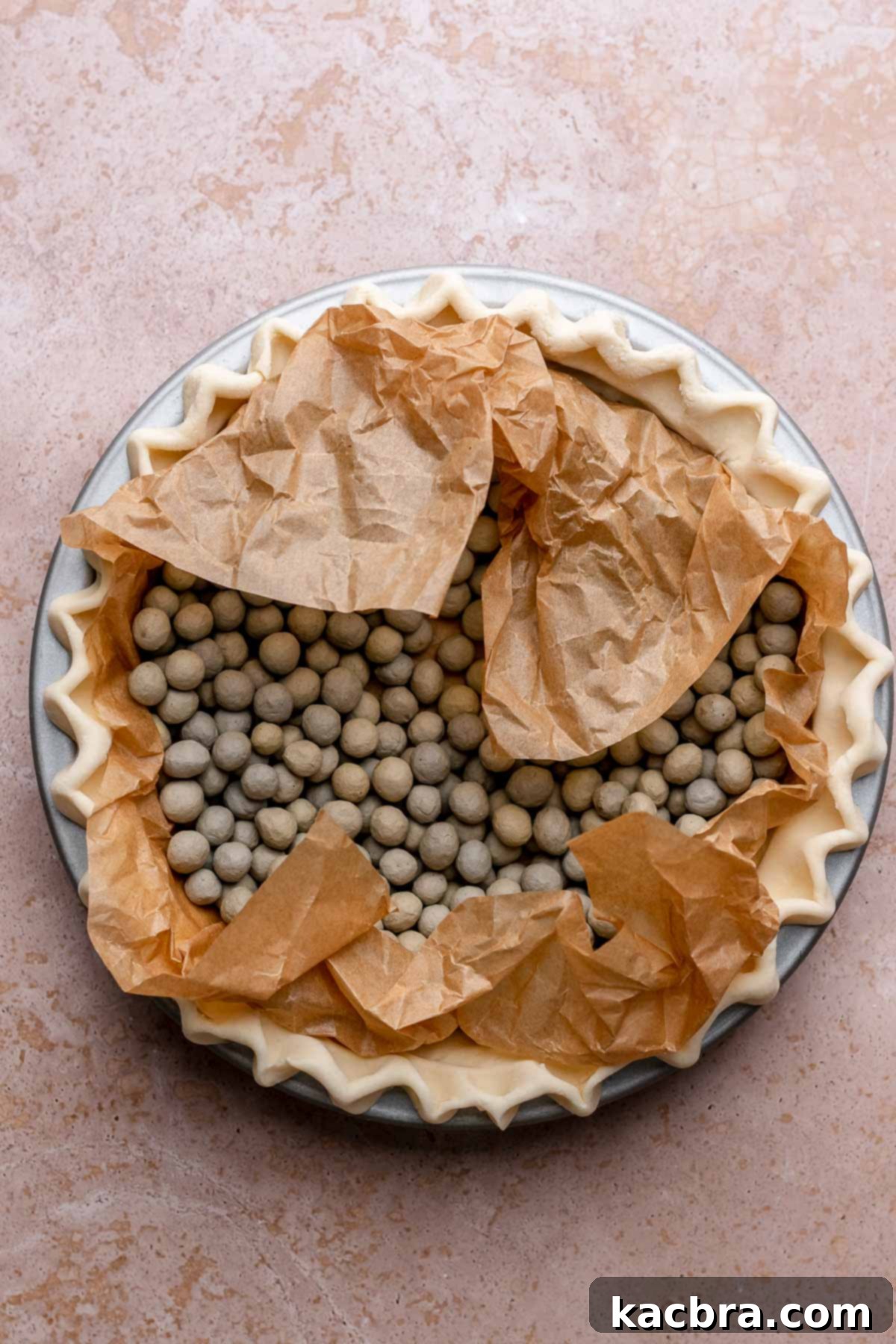 A pie crust with parchment paper and pie weights in it, ready for par-baking.