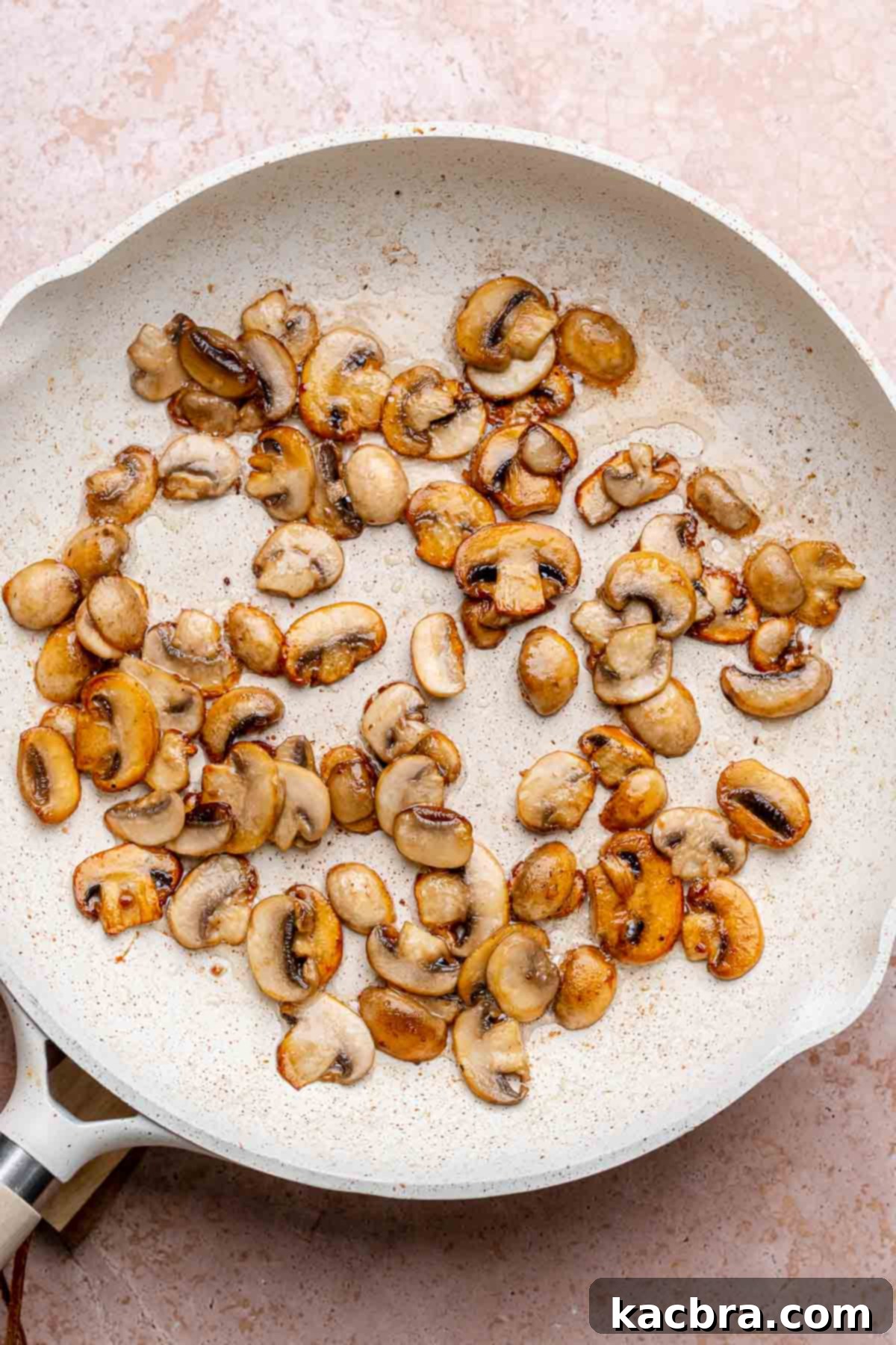 Sautéed mushrooms browning in a pan with bacon fat.