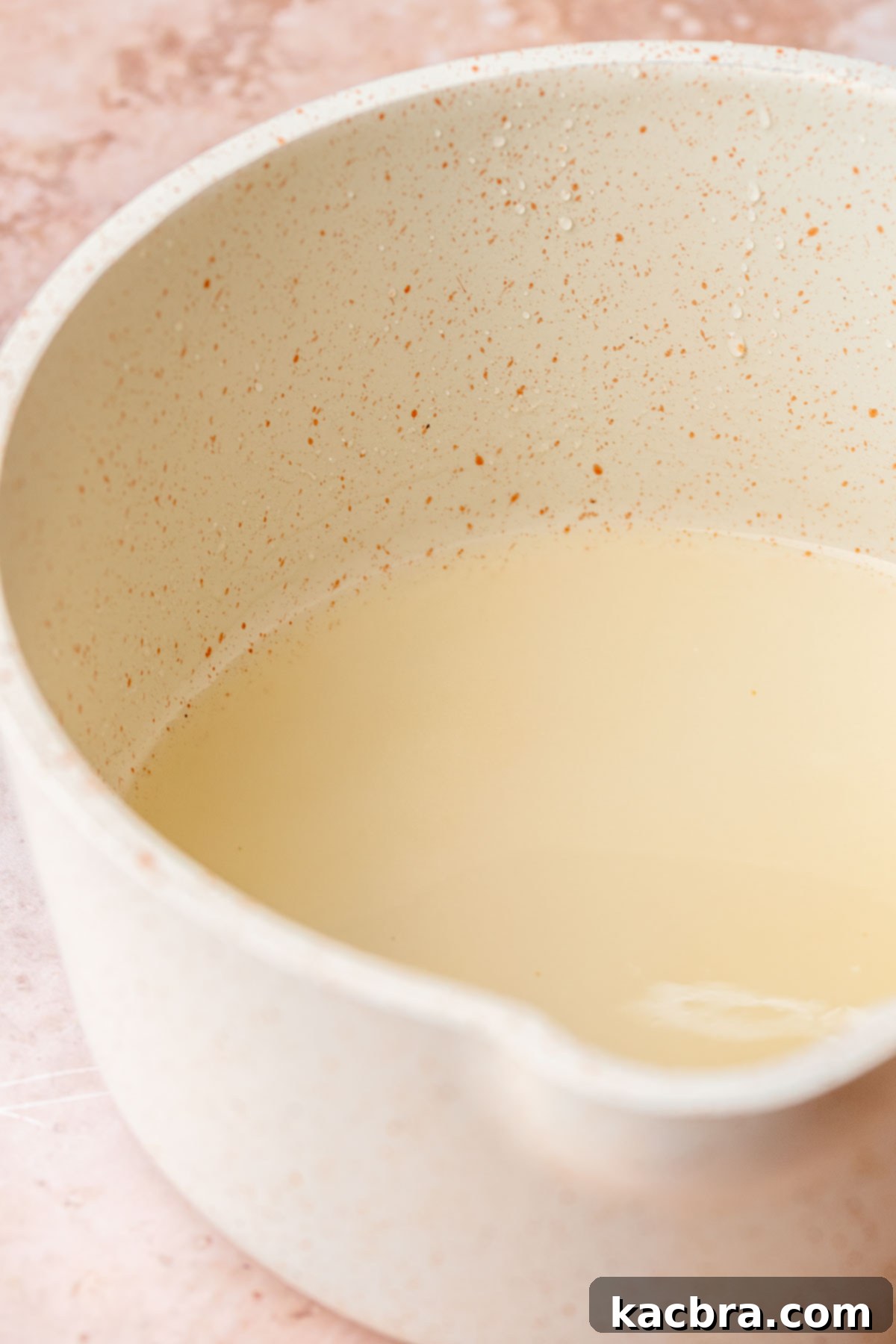 Golden Lemon Pistachio Dream with Honey Mascarpone Cloud 11 Lemon simple syrup simmering in a small saucepan on the stove, creating a clear, sweet liquid.