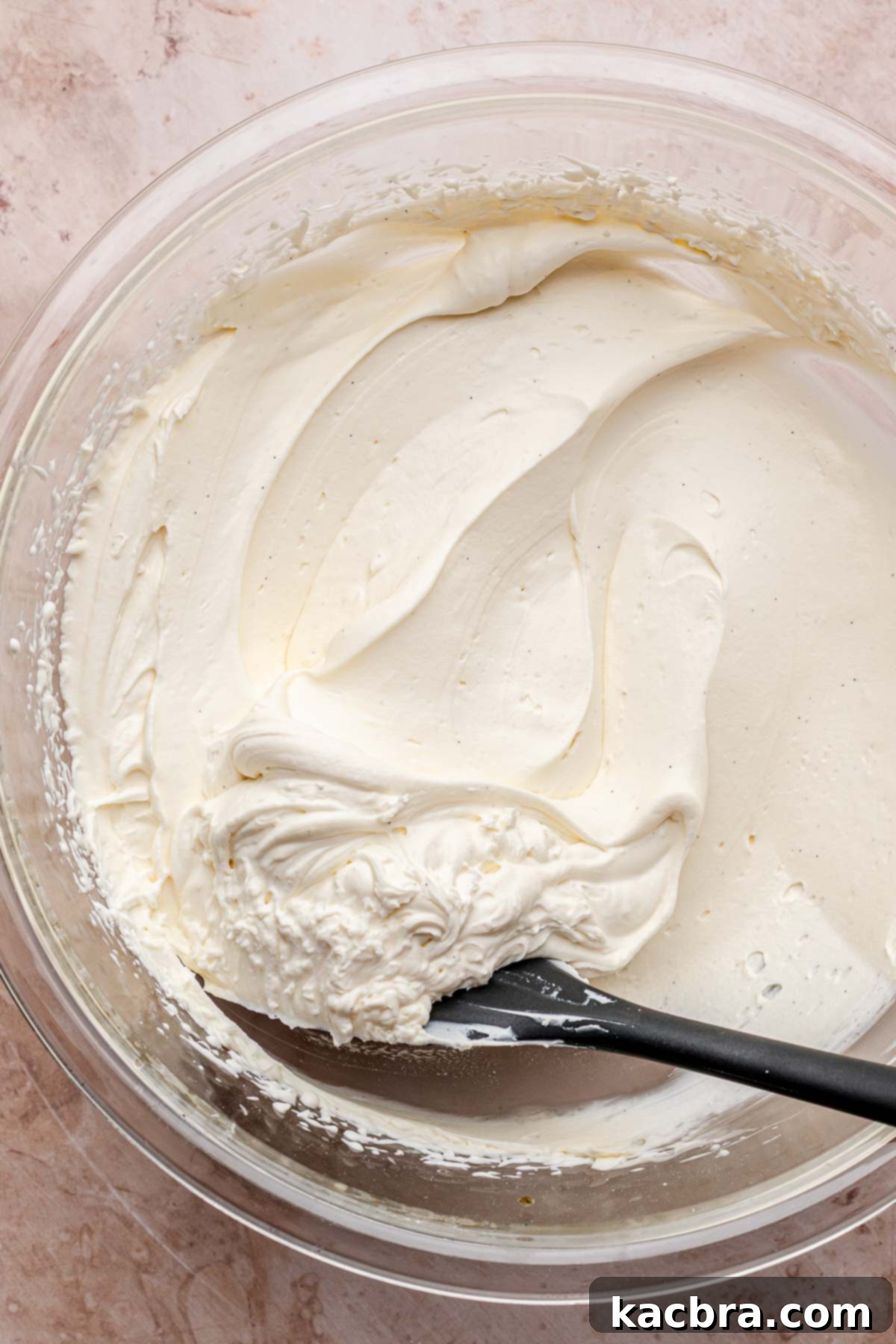 Golden Lemon Pistachio Dream with Honey Mascarpone Cloud 14 Fluffy honey lemon mascarpone frosting in a bowl with a rubber spatula, ready to be spread onto the cake.