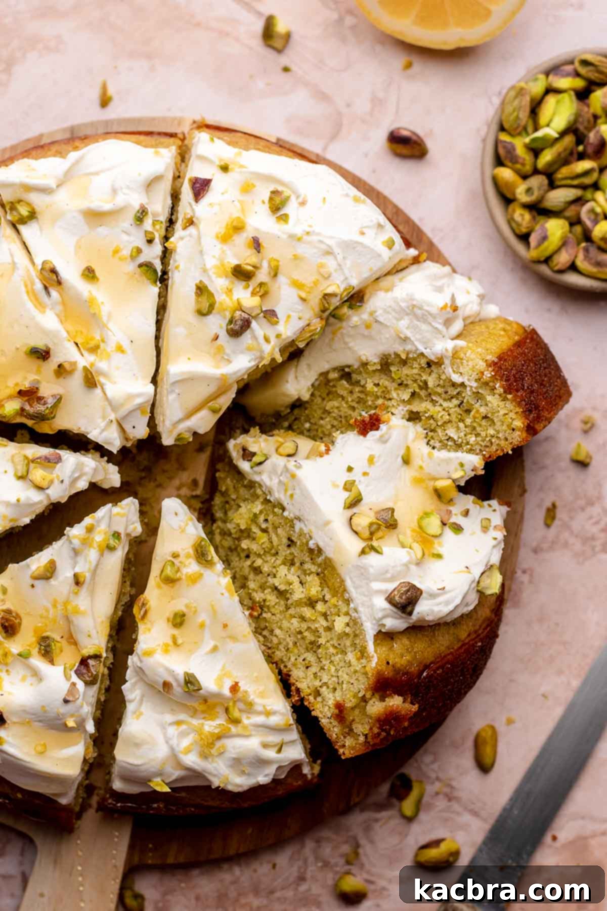 Golden Lemon Pistachio Dream with Honey Mascarpone Cloud 15 A beautifully sliced lemon pistachio cake displayed on a rustic wooden board, ready to be served.