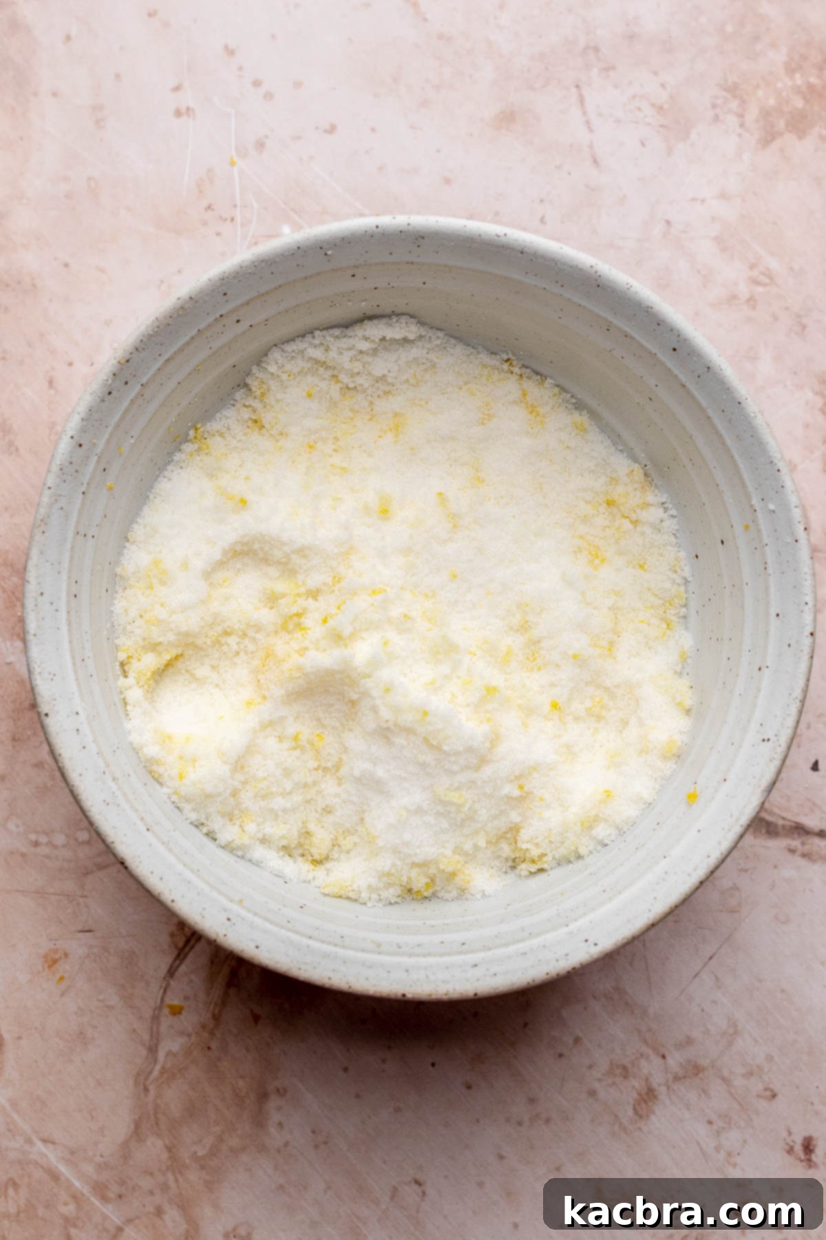 Golden Lemon Pistachio Dream with Honey Mascarpone Cloud 5 Lemon zest being rubbed into granulated sugar in a mixing bowl, creating fragrant lemon sugar.
