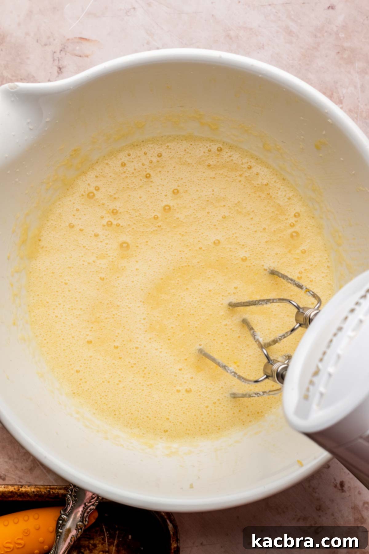 Golden Lemon Pistachio Dream with Honey Mascarpone Cloud 8 A hand mixer blending buttermilk into the wet ingredients, creating a smooth and cohesive batter base.