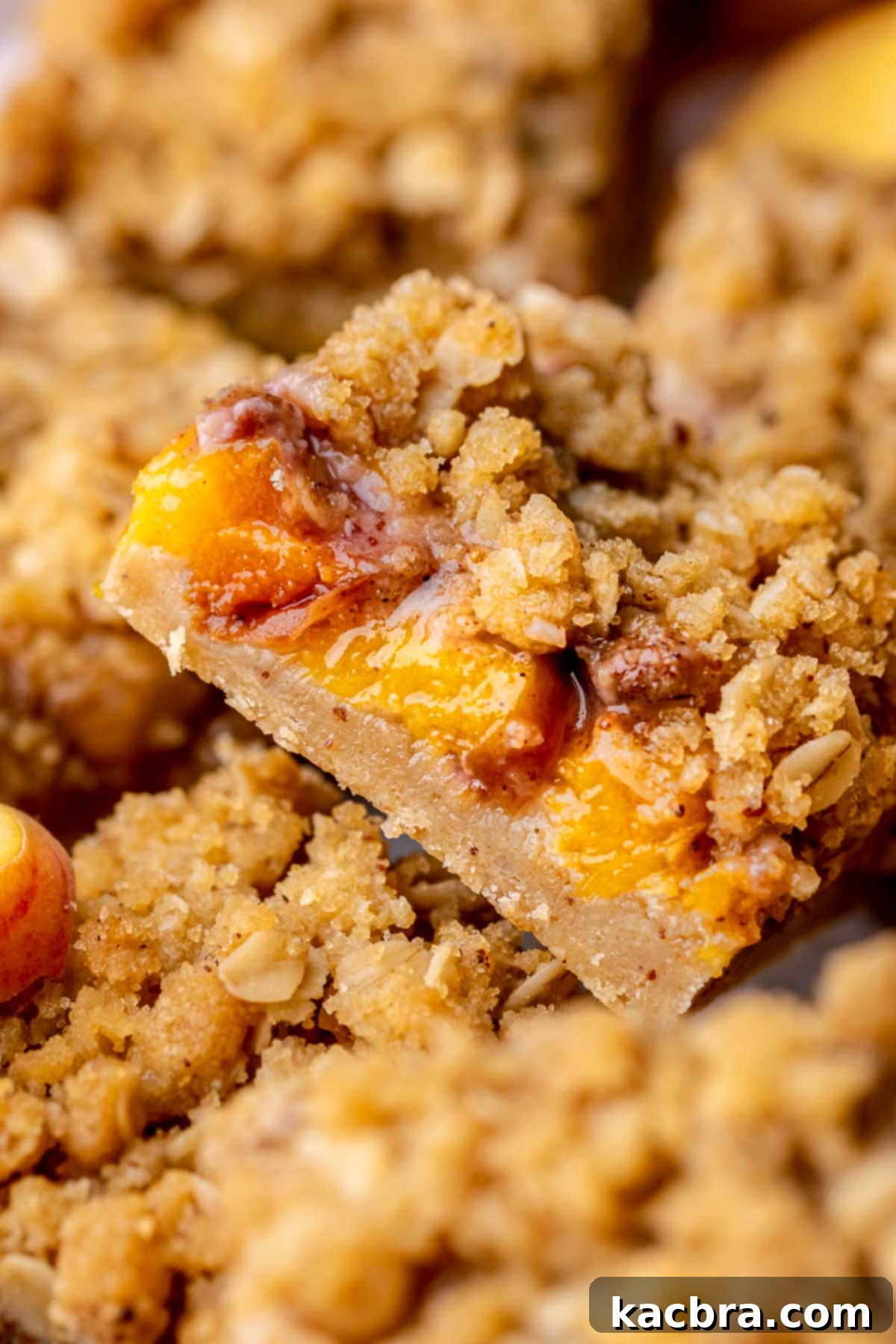 A slice of brown butter peach crumble bars lying on its side, showcasing the layers.
