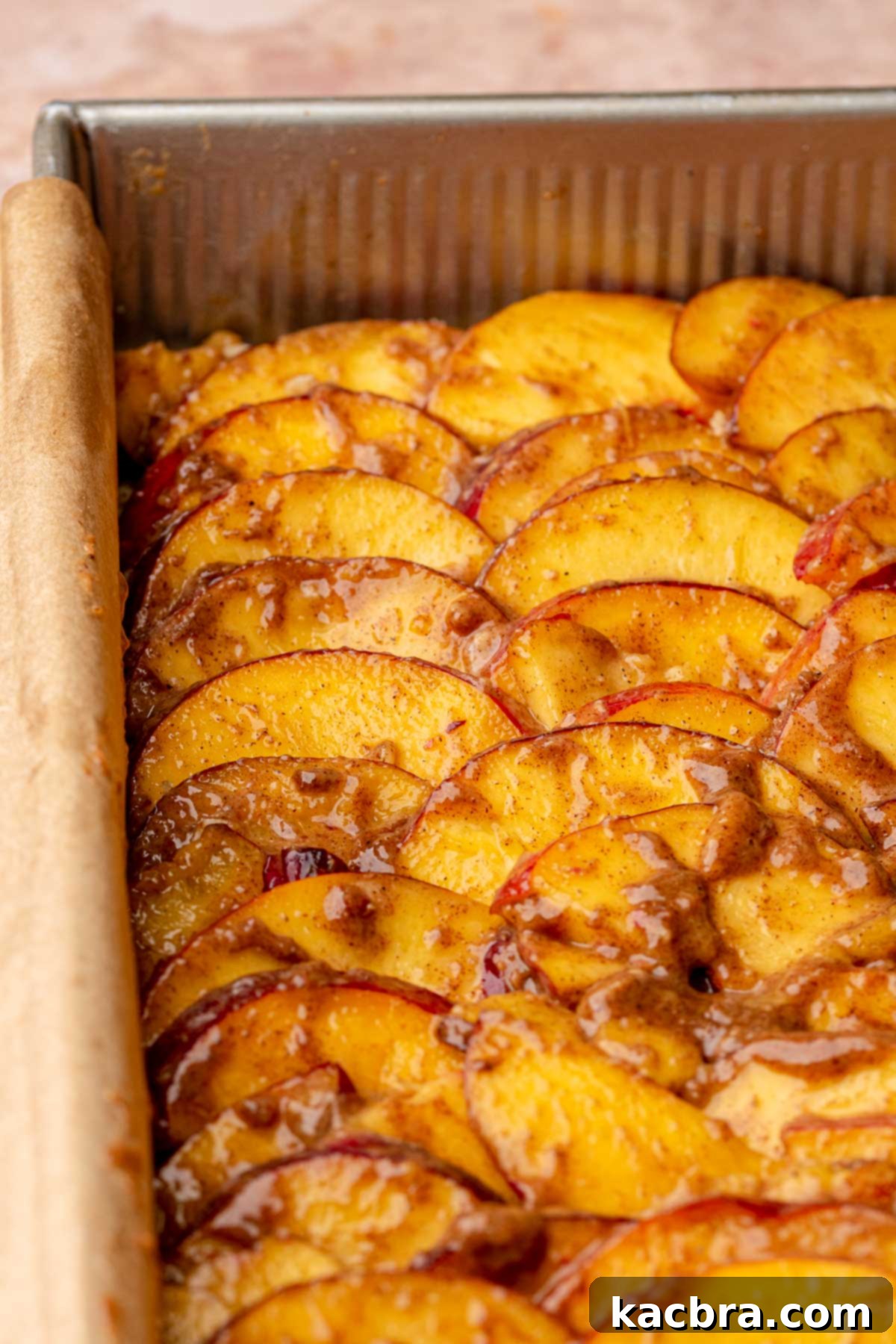Thin peach slices meticulously layered onto the shortbread crust, ready for the final crumble.