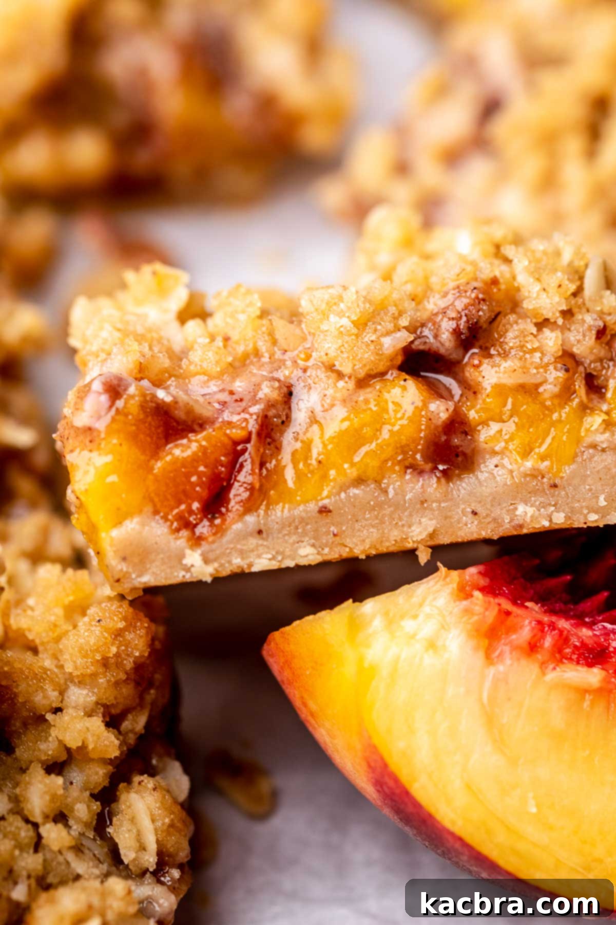 A beautiful slice of peach crumble bar, perfectly showcasing the layers, lying on its side.