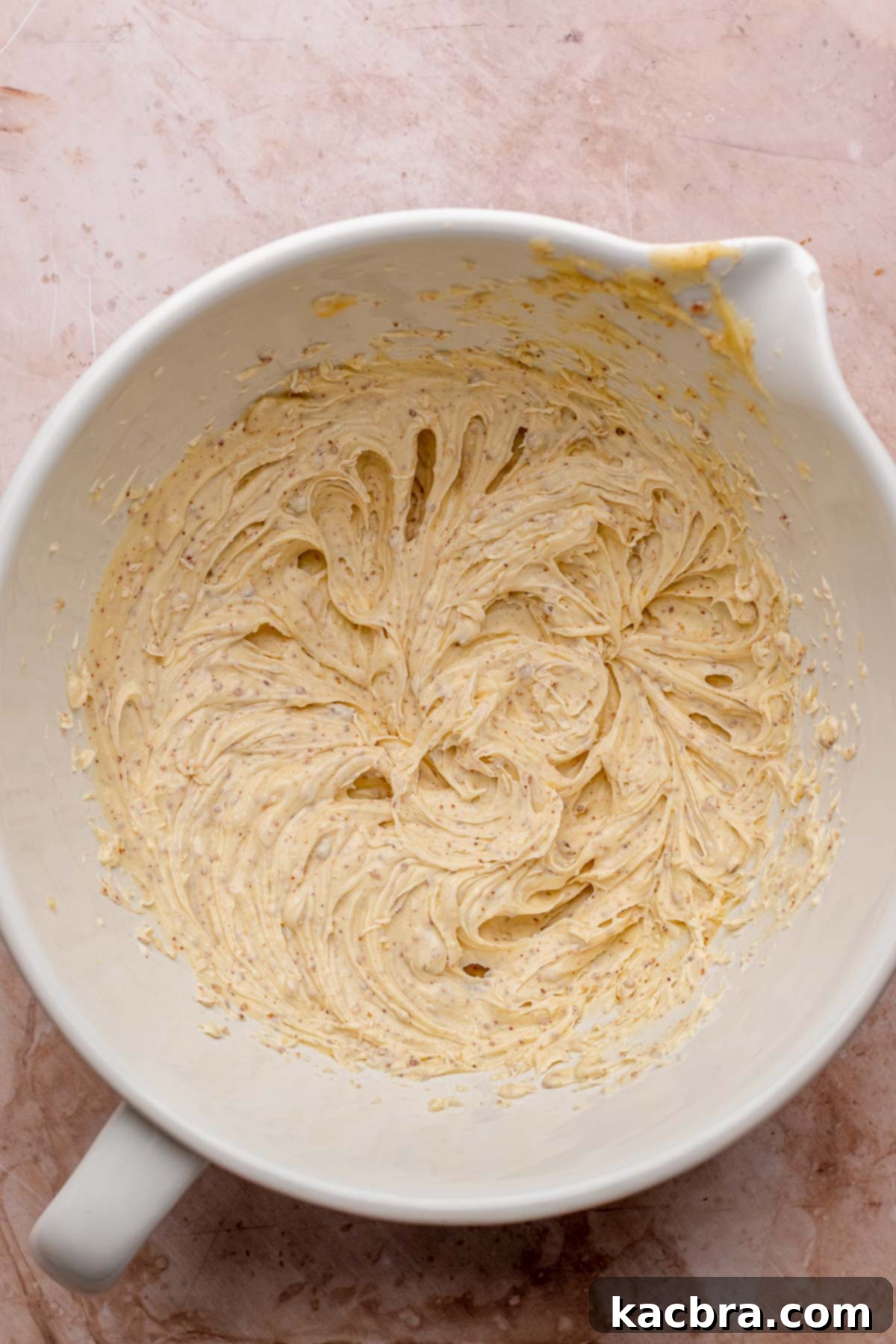 Softened, whipped brown butter in a mixing bowl, light and fluffy.