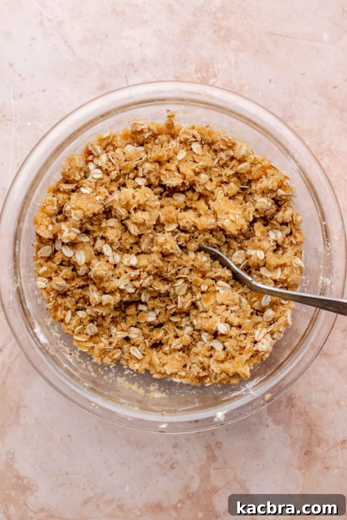 A fork mixing streusel crumbles in a bowl, demonstrating the perfect texture of the topping.