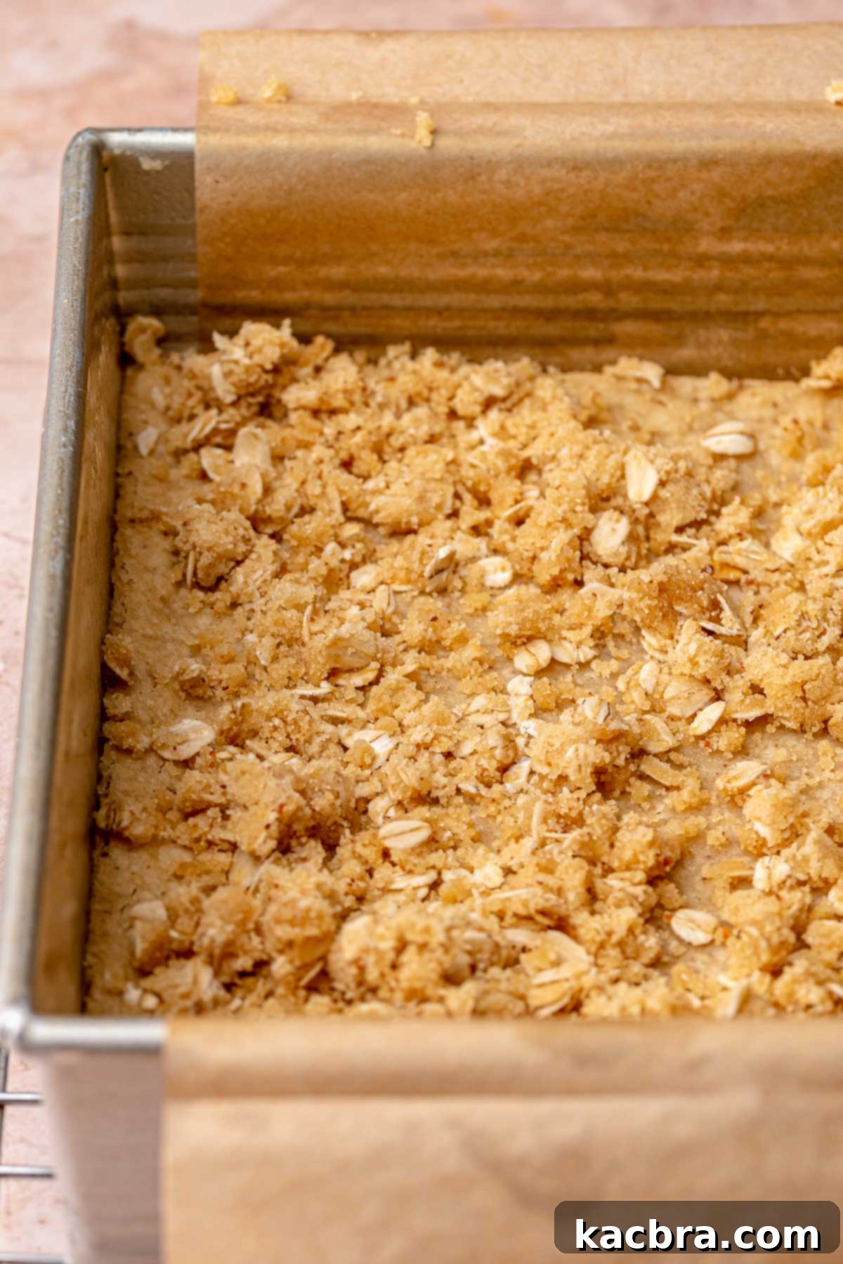 Pieces of oatmeal crumble evenly sprinkled over a partially baked shortbread crust.