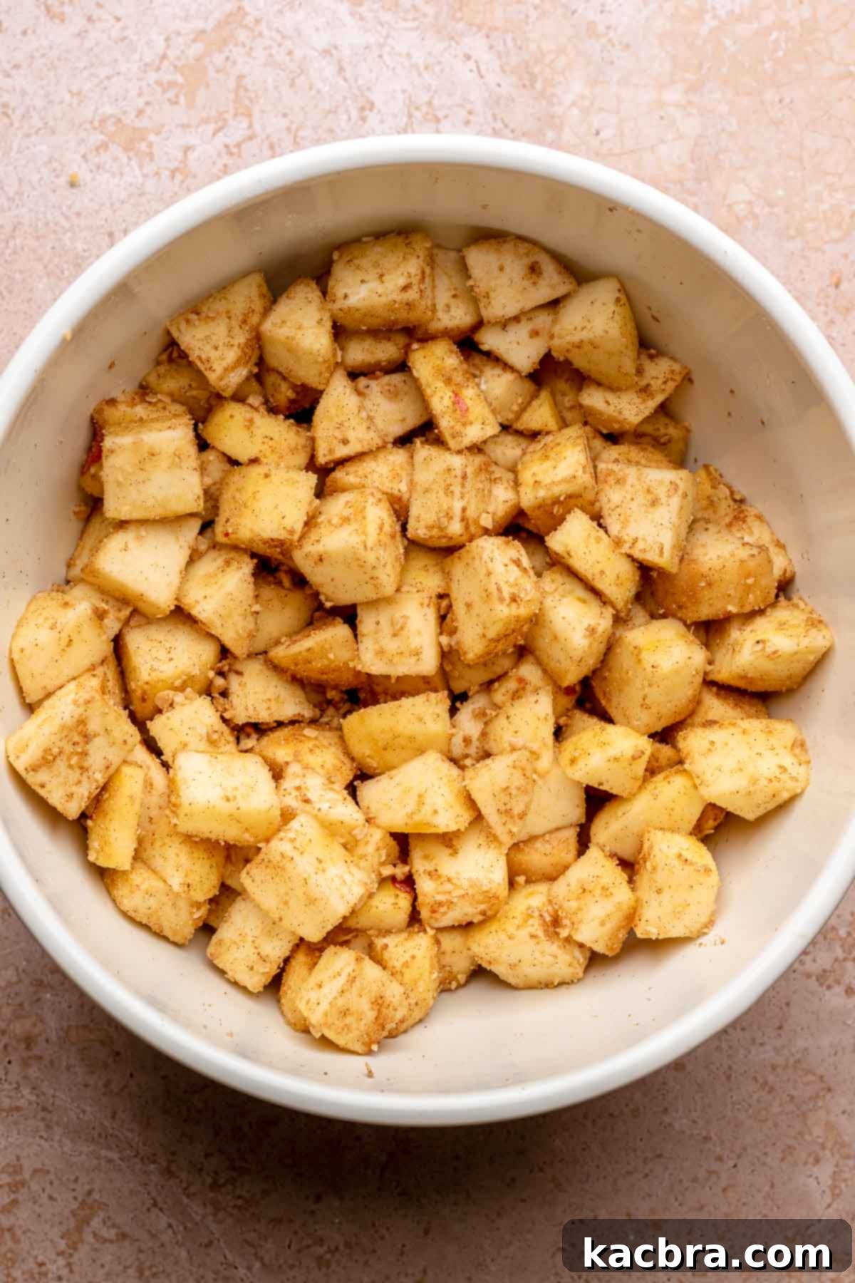 Chopped apples tossed with cinnamon, brown sugar, and flour in a large mixing bowl, ready for the baking dish.