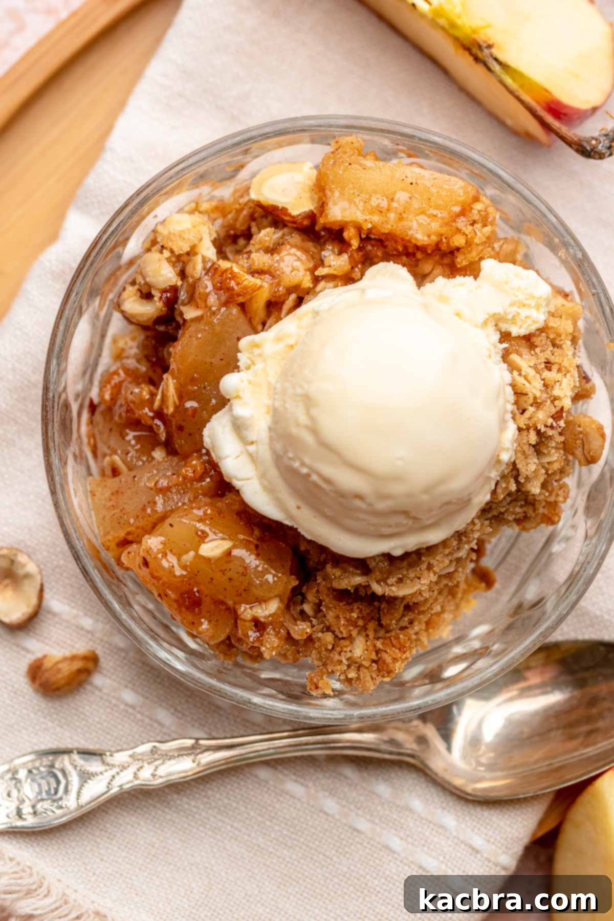 A serving of Toffee Apple Hazelnut Crumble in a bowl, crowned with melting vanilla ice cream.