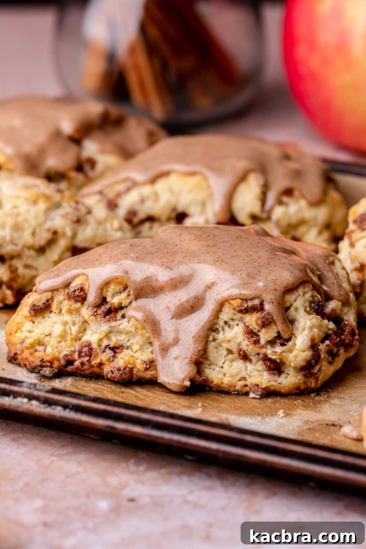An iced cinnamon apple scone on a sheet pan, showcasing its golden crust and sweet glaze.