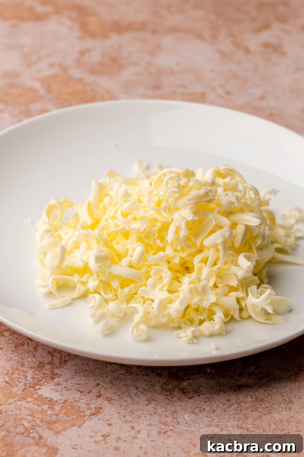 A mound of finely grated frozen butter on a plate, ready to be incorporated into scone dough.