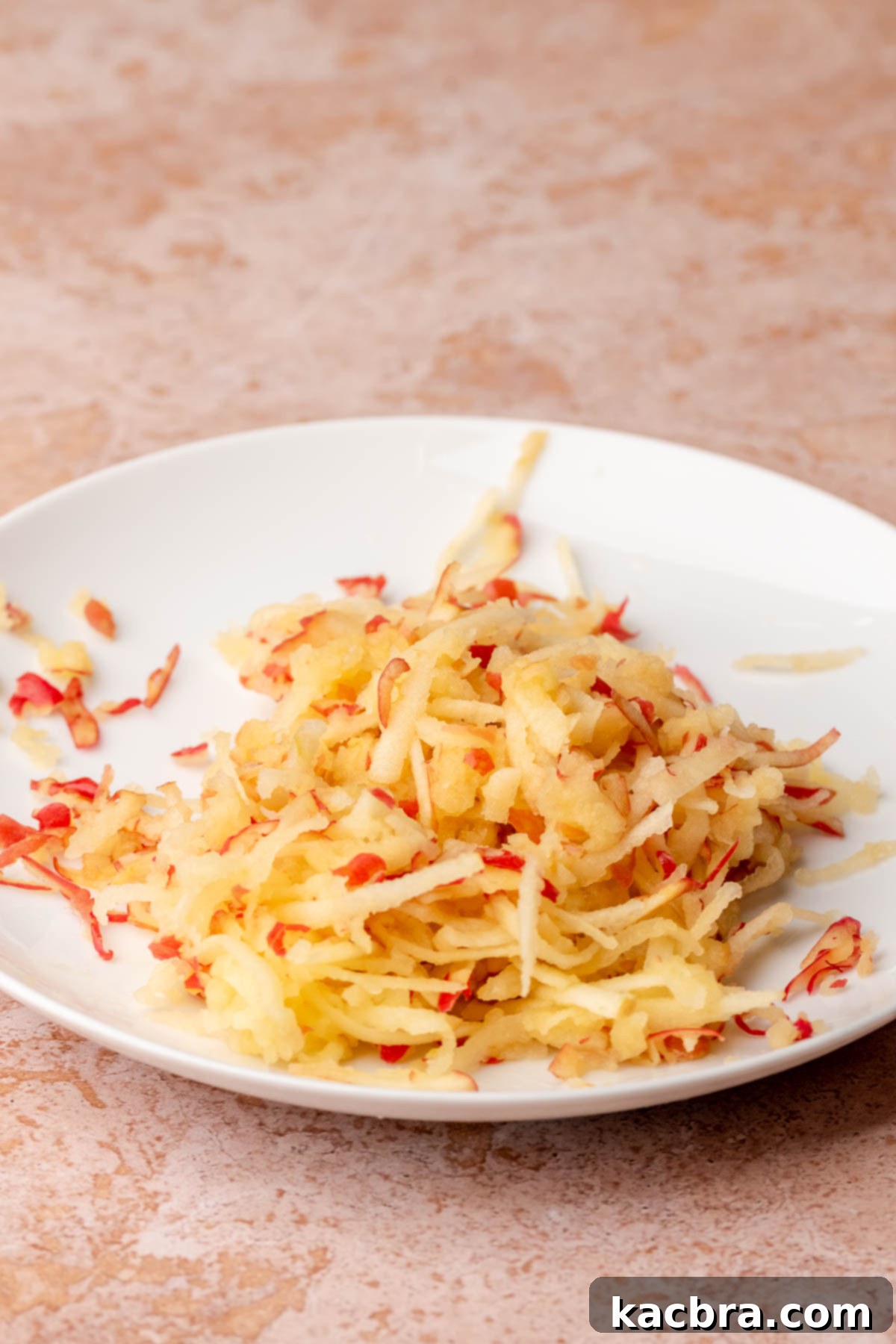 A small pile of grated apples on a plate, showing their moist texture.