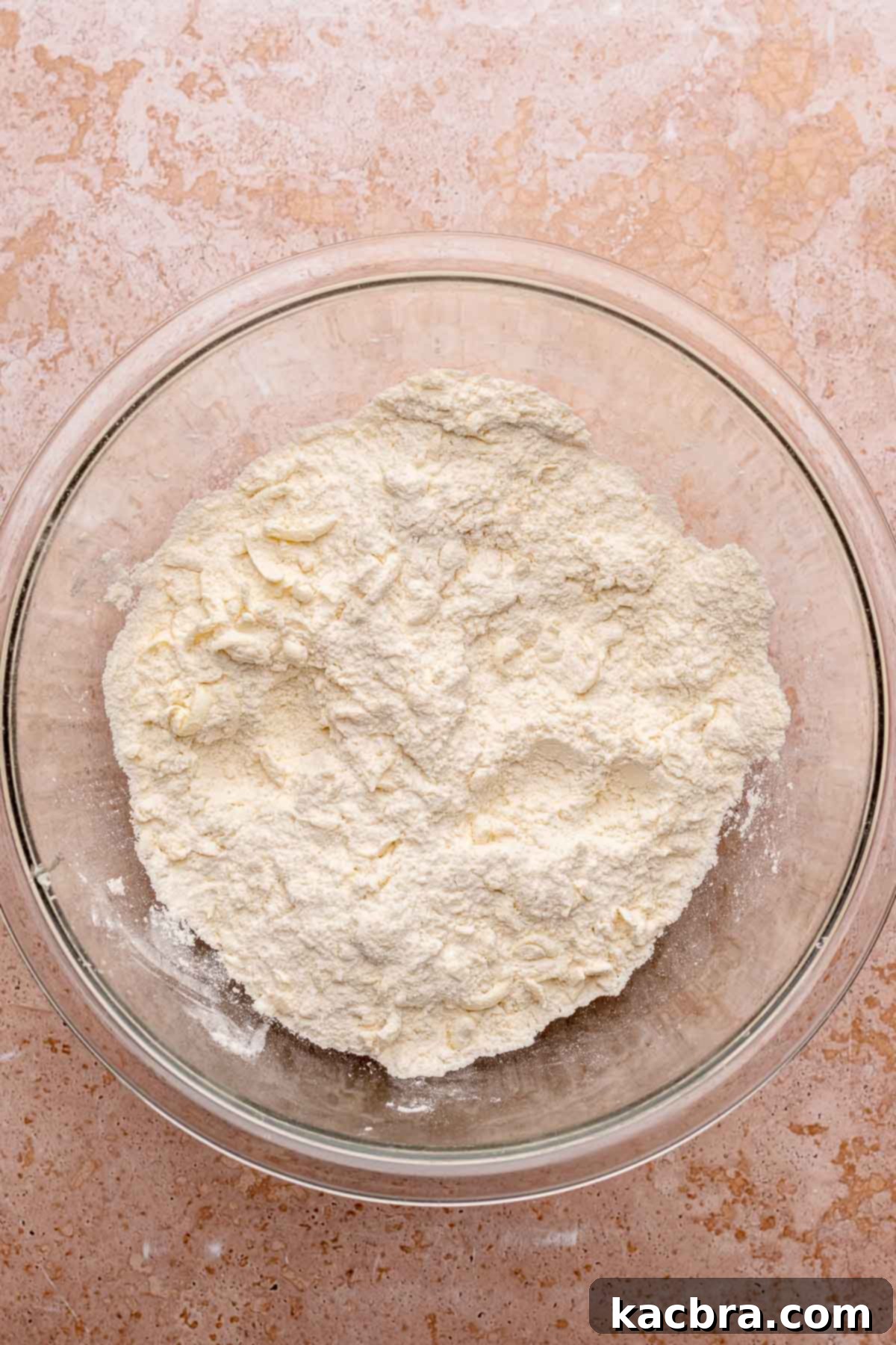 A large mixing bowl filled with flour, sugar, baking powder, salt, and shreds of frozen butter.