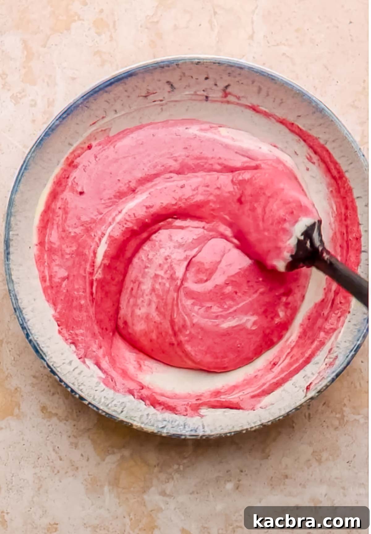 Cranberry puree is gently folded into a portion of the cheesecake batter with a spatula, creating a beautifully tinted, swirled mixture.