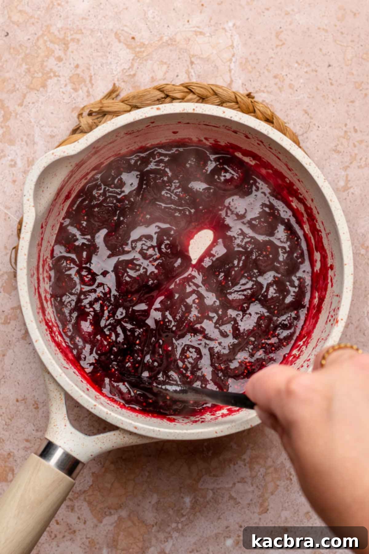 Fresh cranberries, sugar, and spices cooking down in a pot, creating a vibrant red puree for the cheesecake bars.
