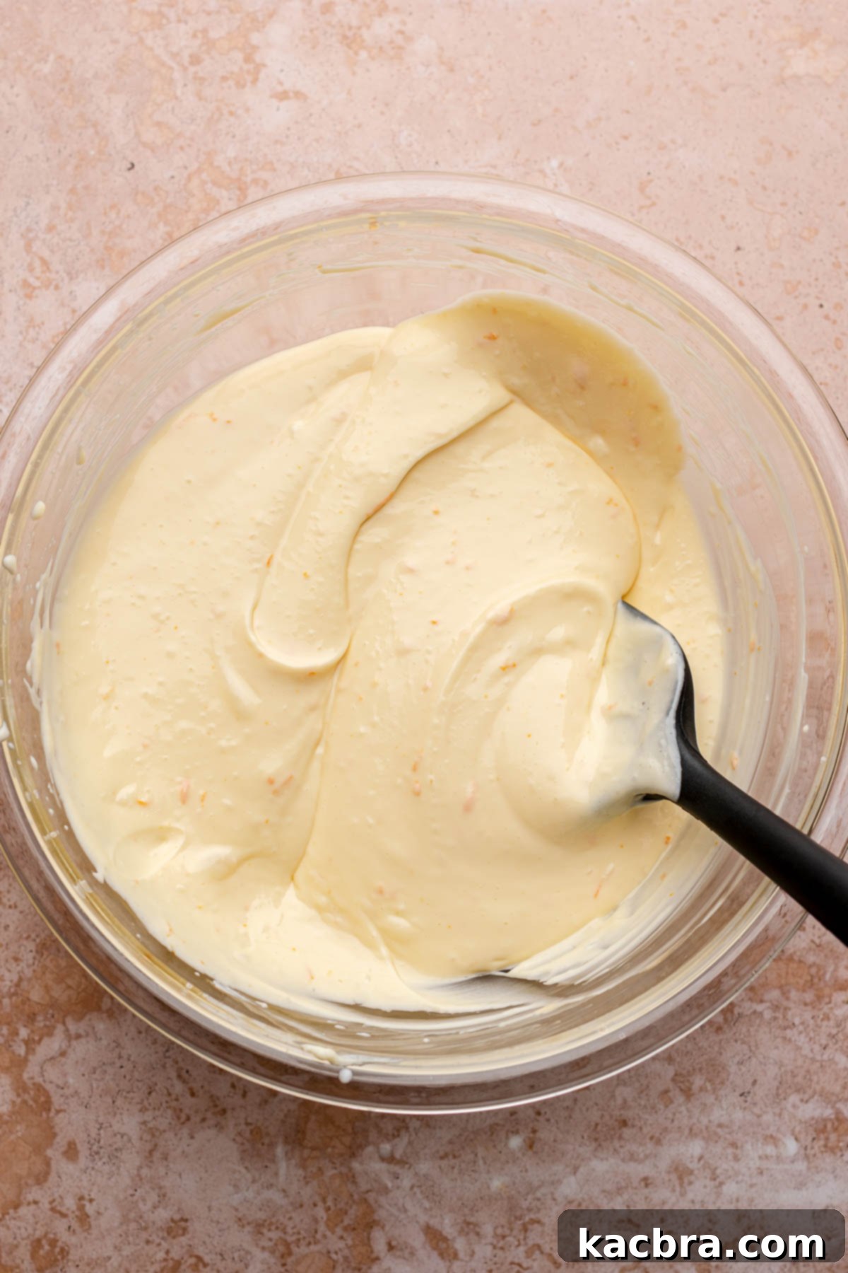 The finished, smooth cheesecake batter rests in a mixing bowl, perfectly prepared for assembly with the cranberry puree.