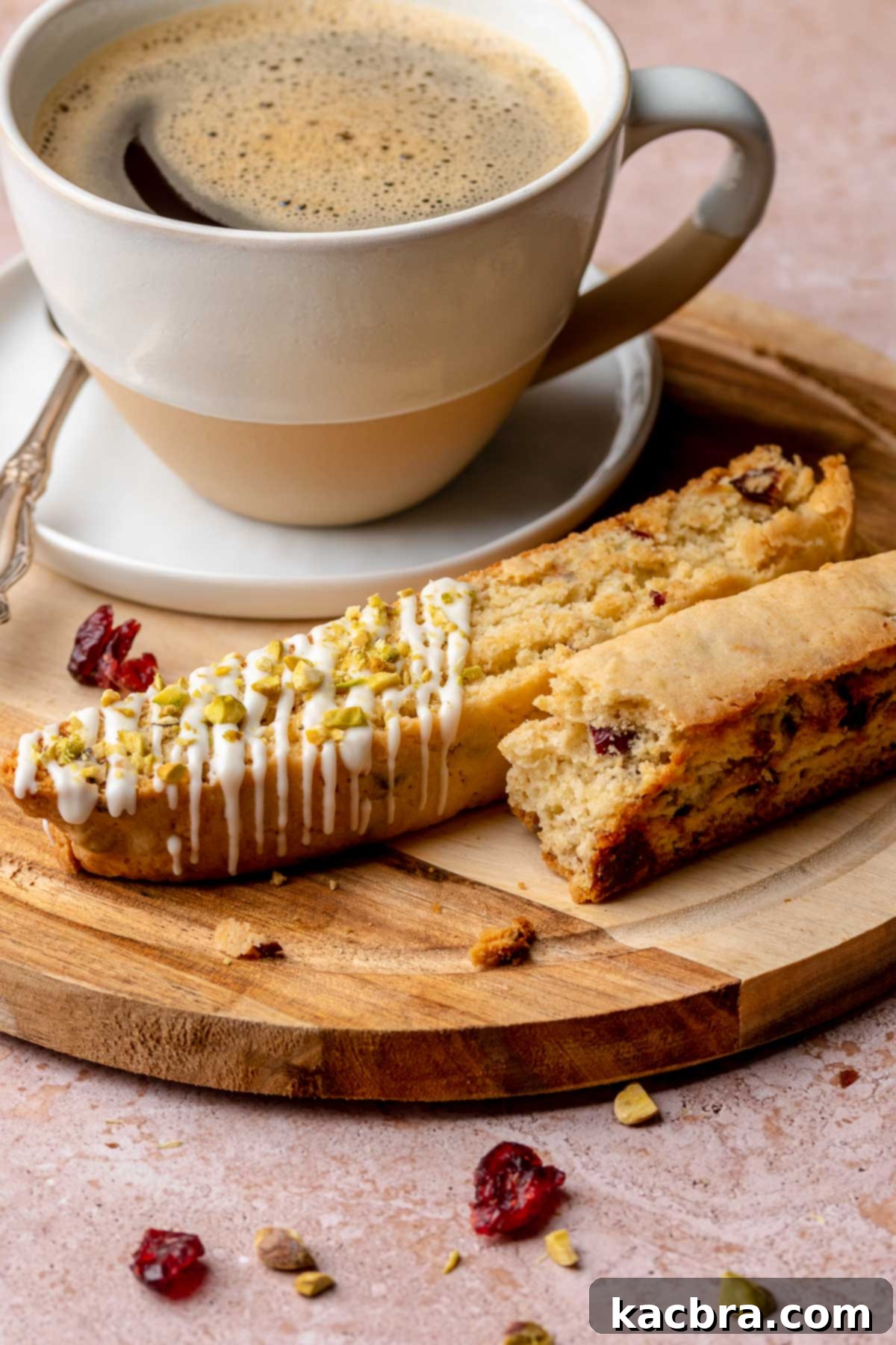 Pistachio biscotti pieces on a plate with a coffee cup.