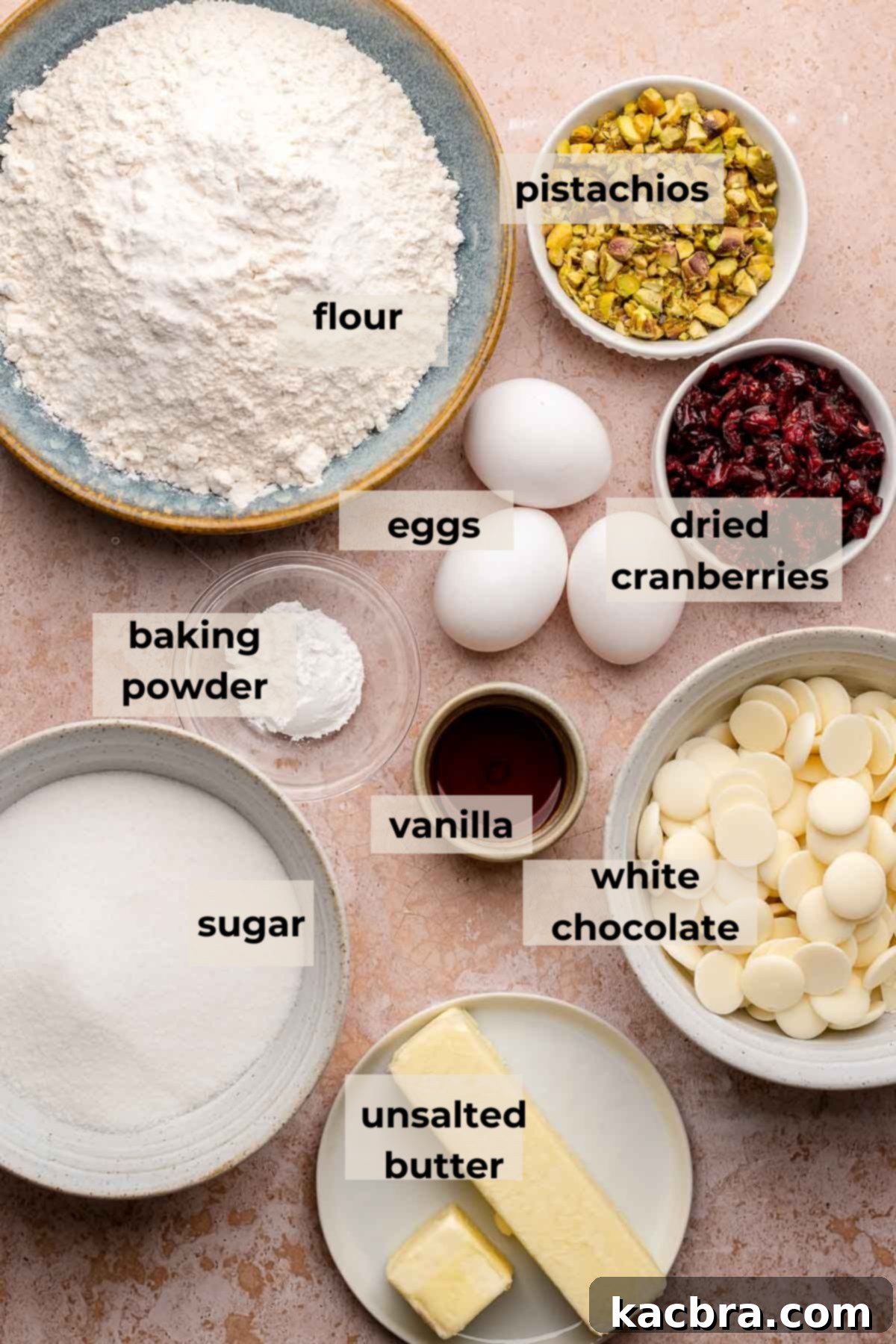 A selection of fresh ingredients including flour, butter, eggs, pistachios, and dried cranberries, ready for making biscotti.