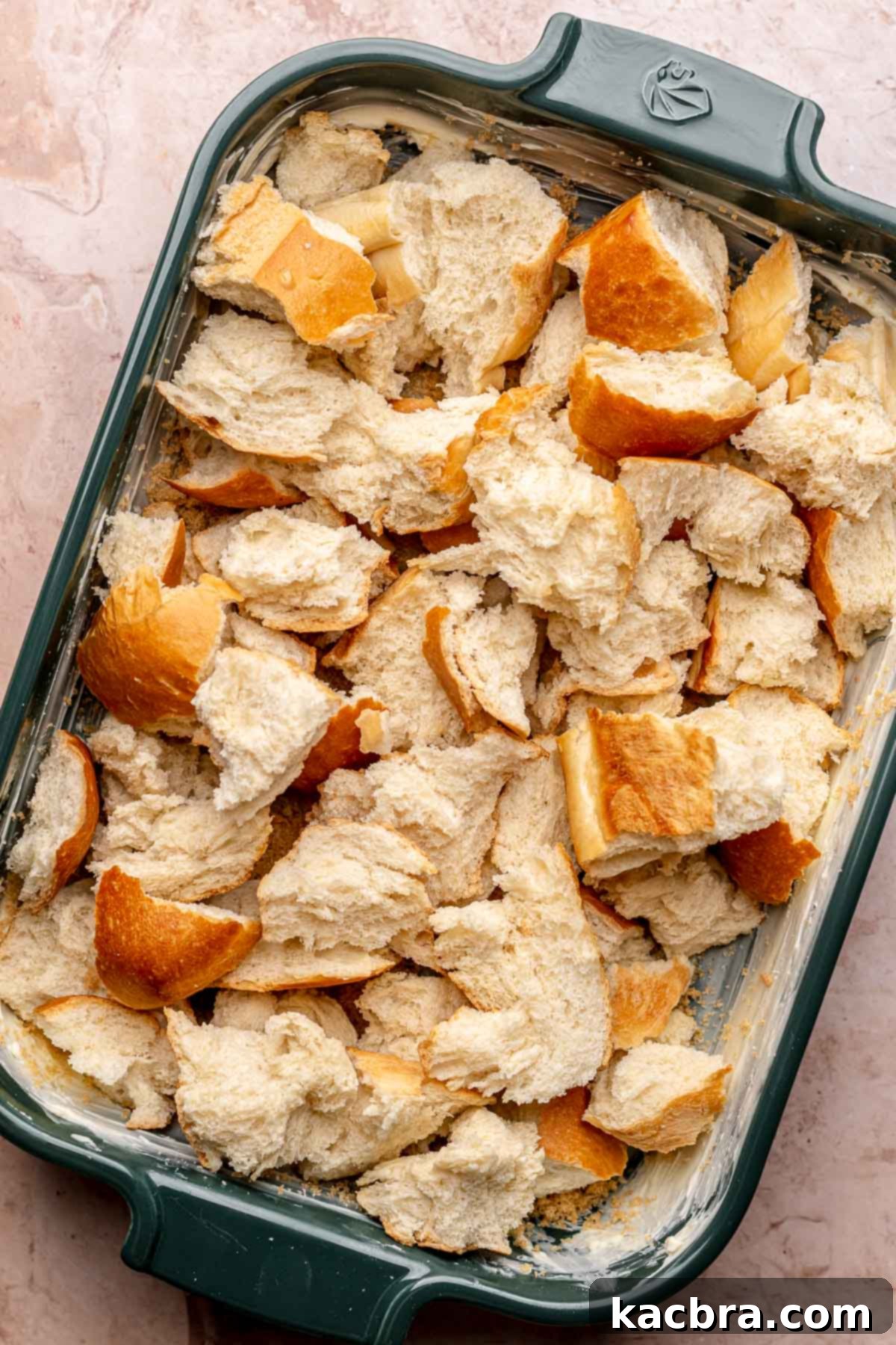 Torn pieces of bread layered in a casserole dish, second step.