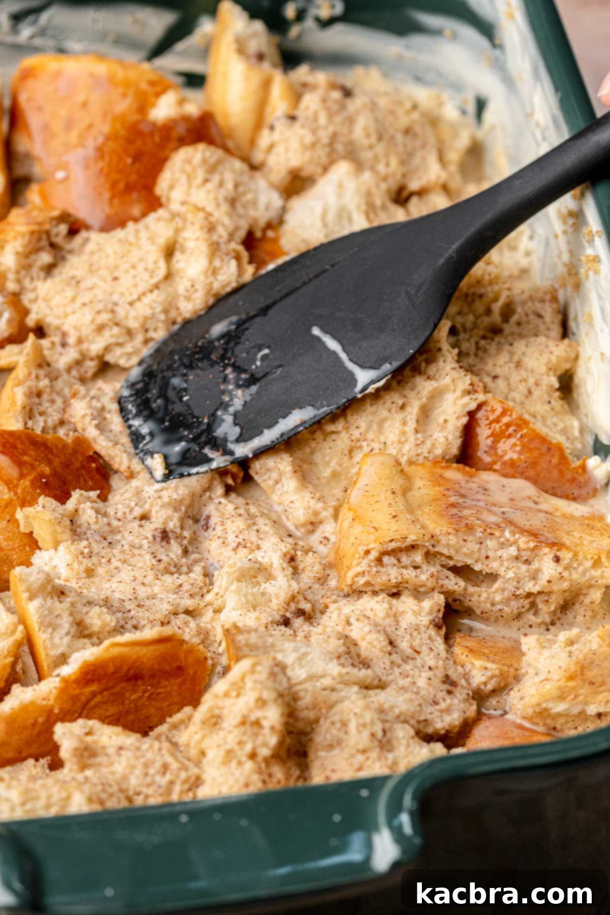 A spatula gently pushes the bread down into the custard to ensure full soaking, fifth step.