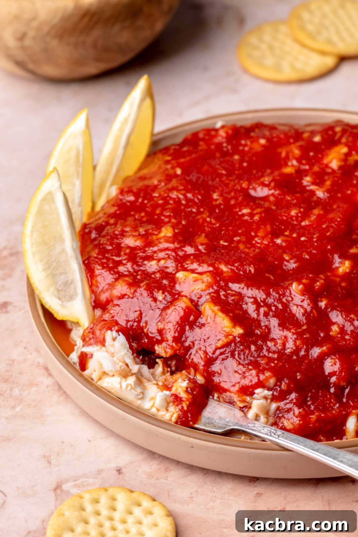 A finished cream cheese crab dip on a decorative plate with a serving knife.
