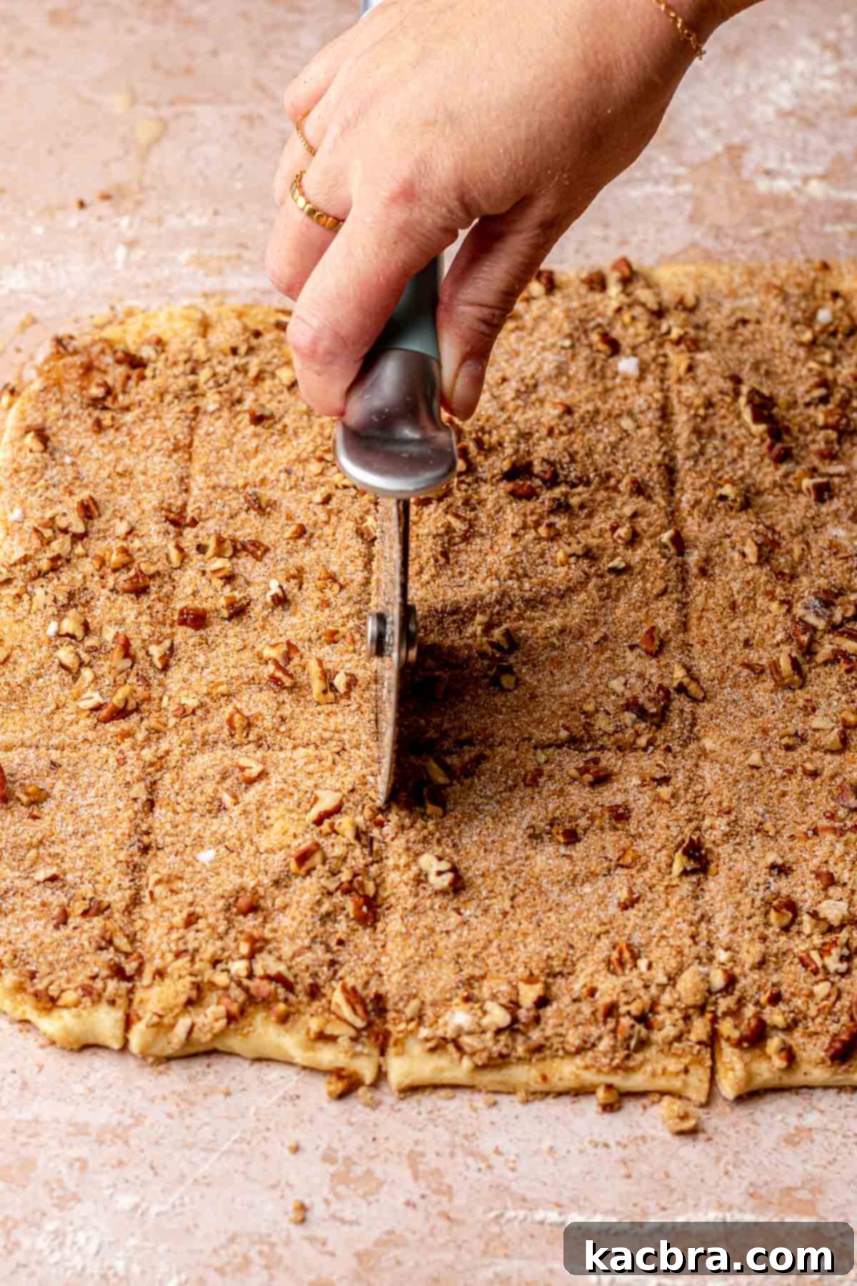 A pizza wheel cutting dough into small, uniform rectangles.