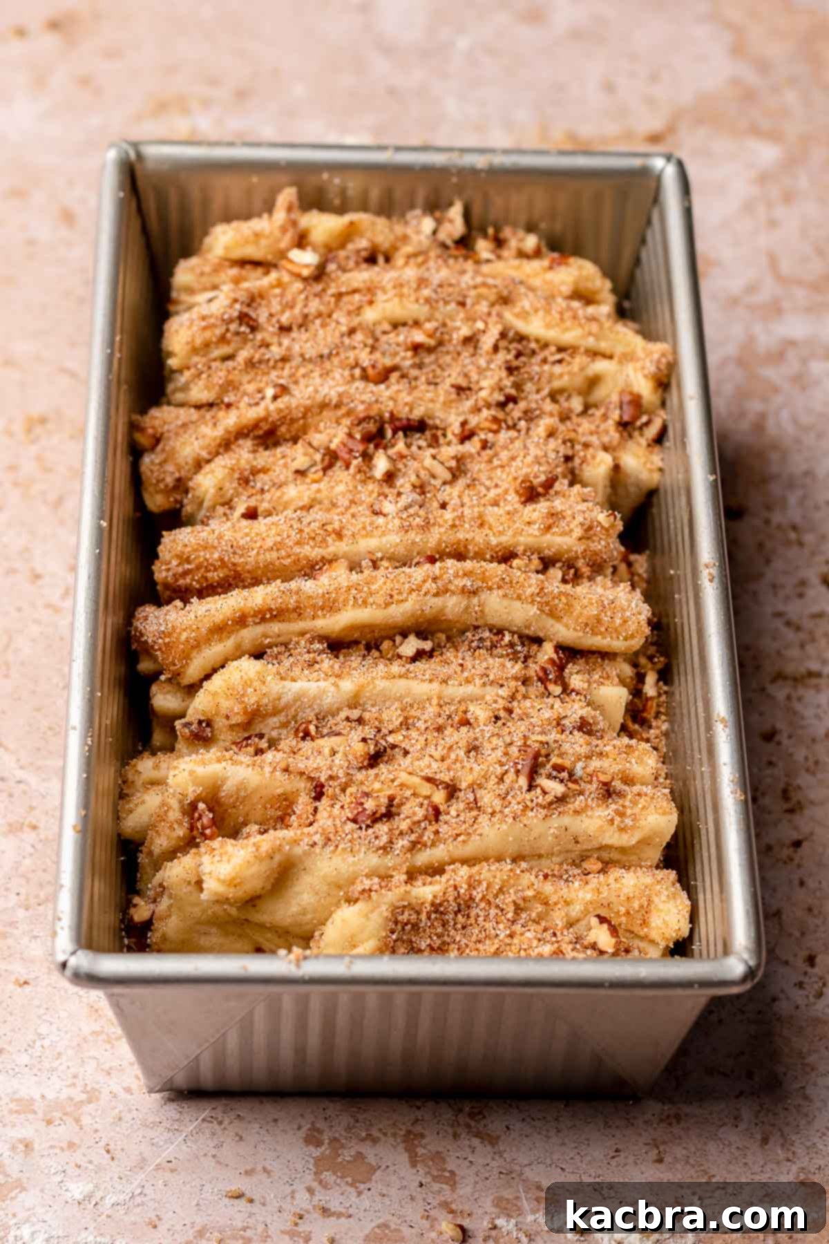 Dough pieces layered upright in a loaf pan before their second rise.