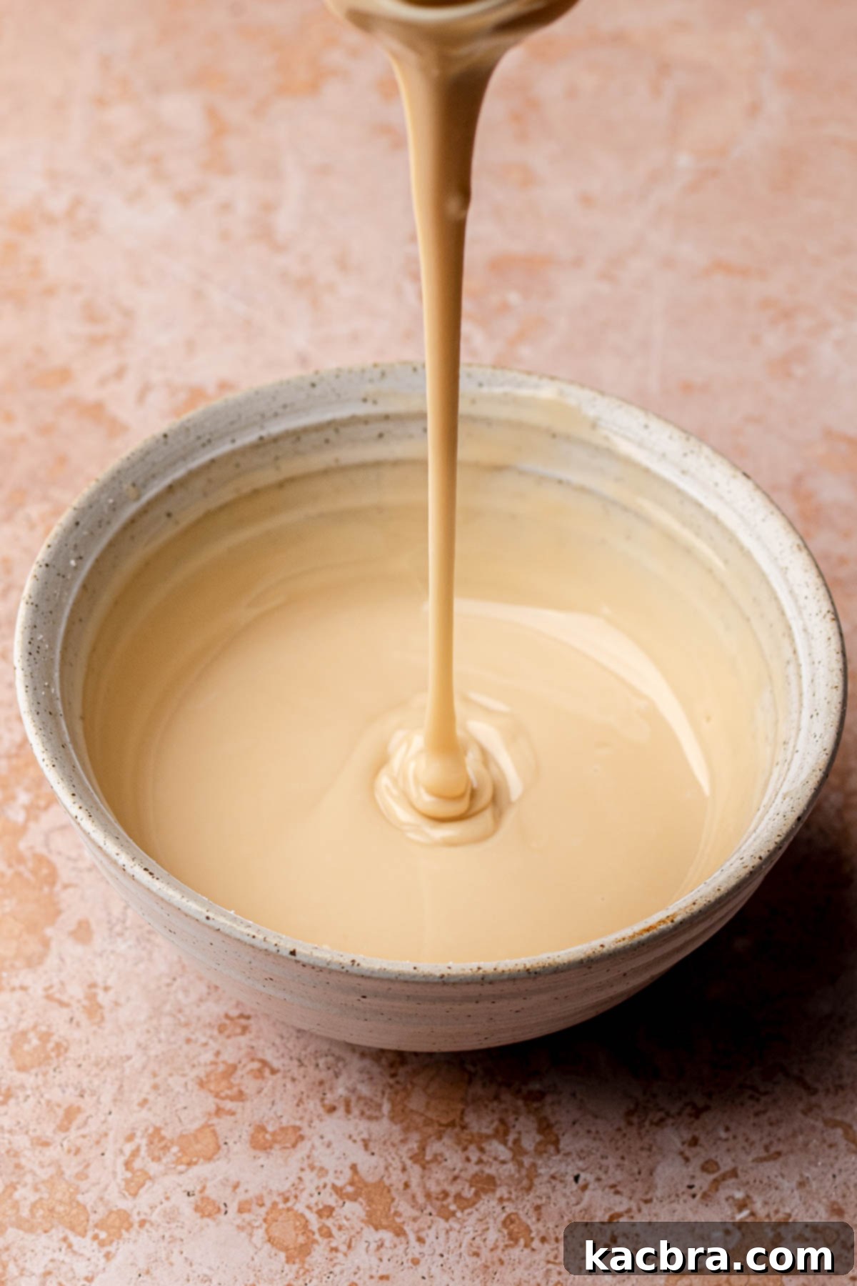 A whisk smoothly mixing maple glaze ingredients in a bowl.