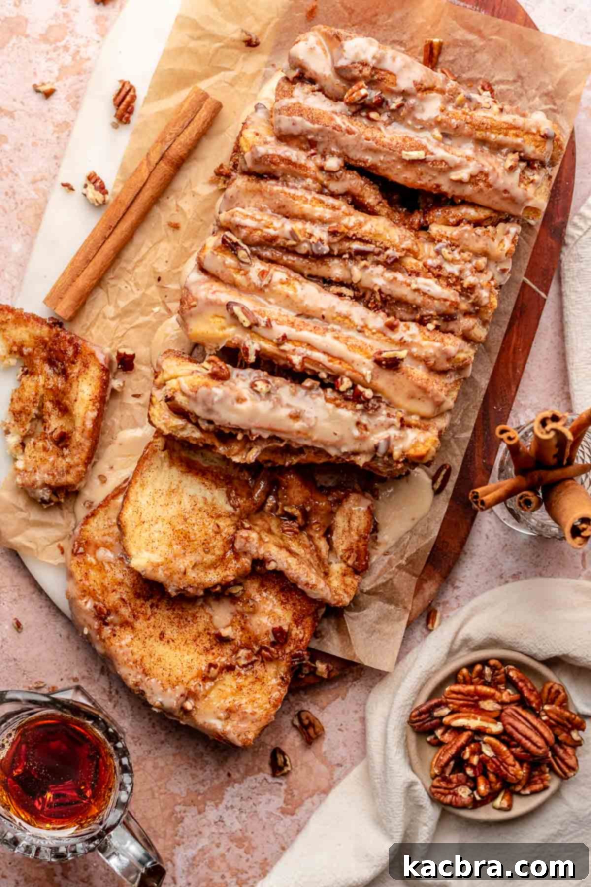 Maple Pecan Cinnamon Pull Apart Bread on a wooden cutting board, with a few pieces pulled down for serving.