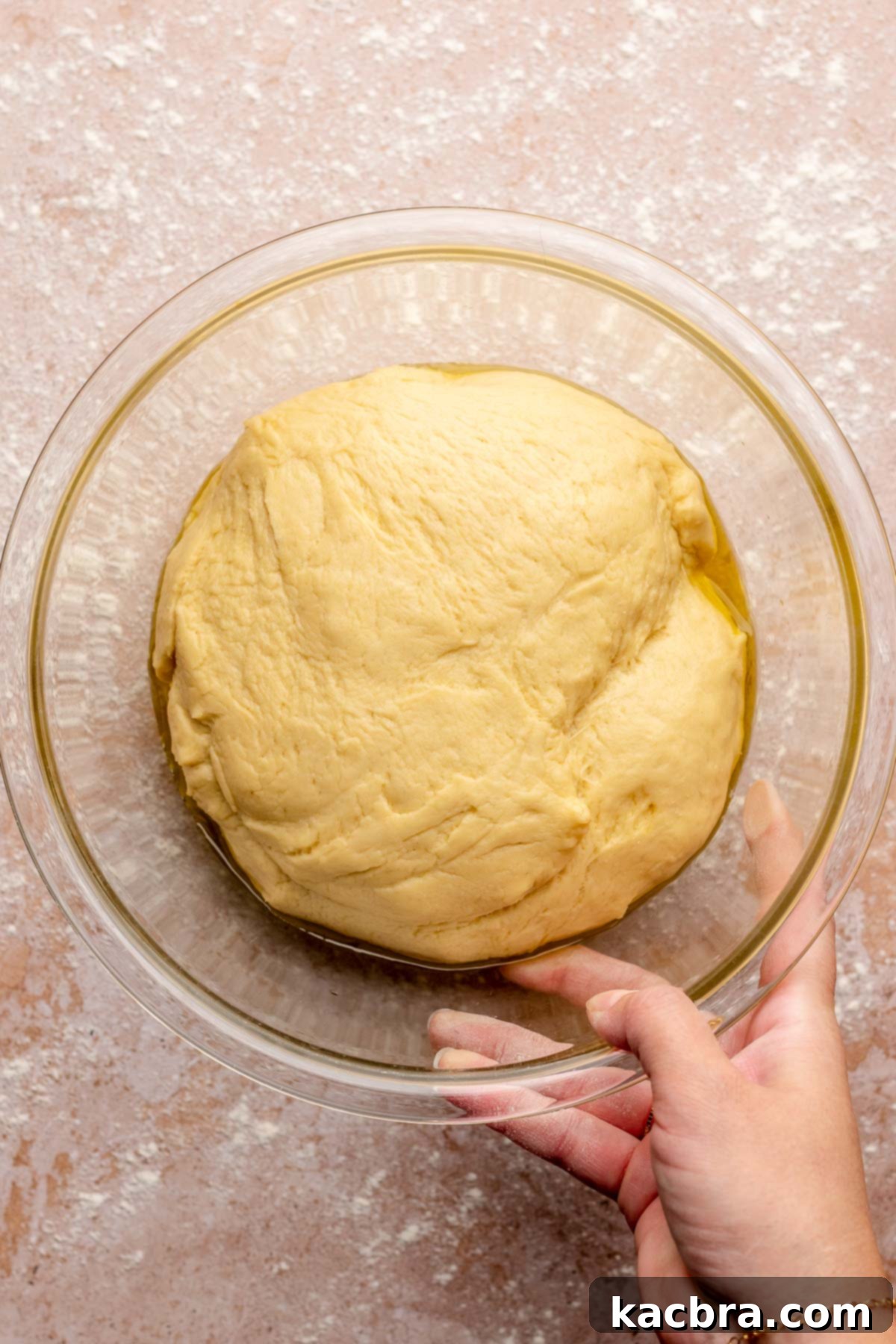 Fully risen ball of dough in a mixing bowl, ready for shaping.