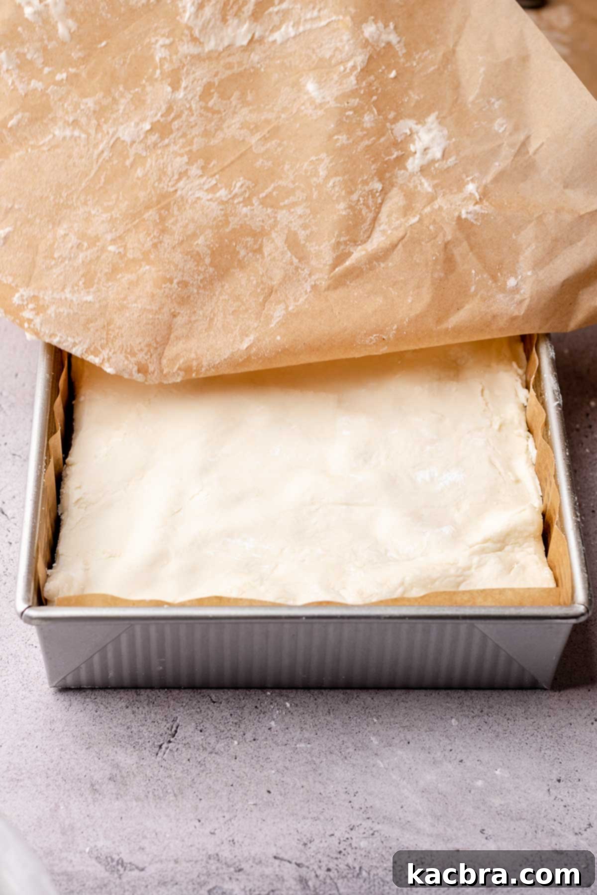 Peppermint filling is added on top of brownies in a square pan.