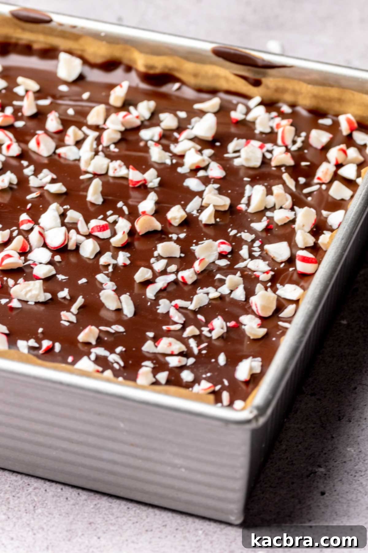 Peppermint candies spread on top of chocolate ganache brownies in a pan.