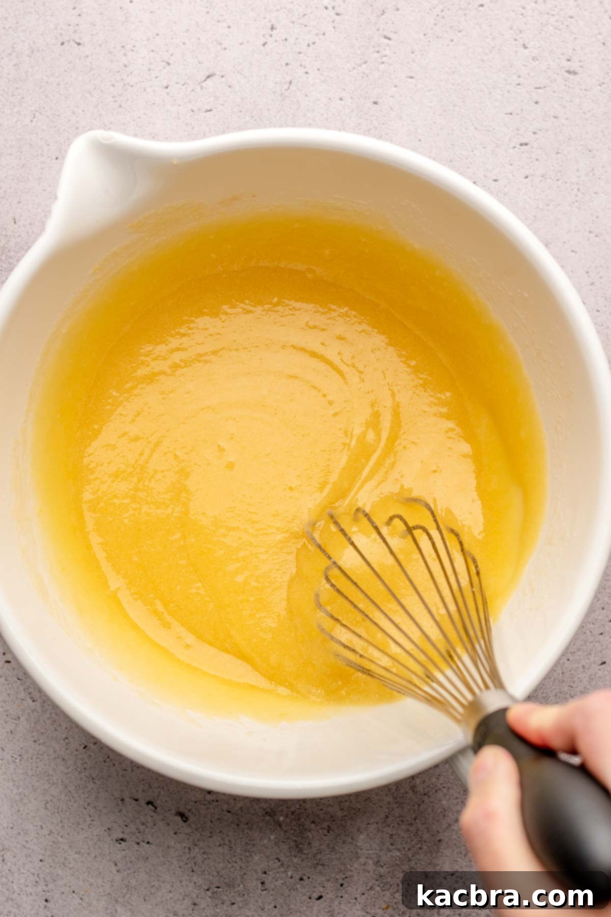A whisk mixes wet ingredients in a bowl.