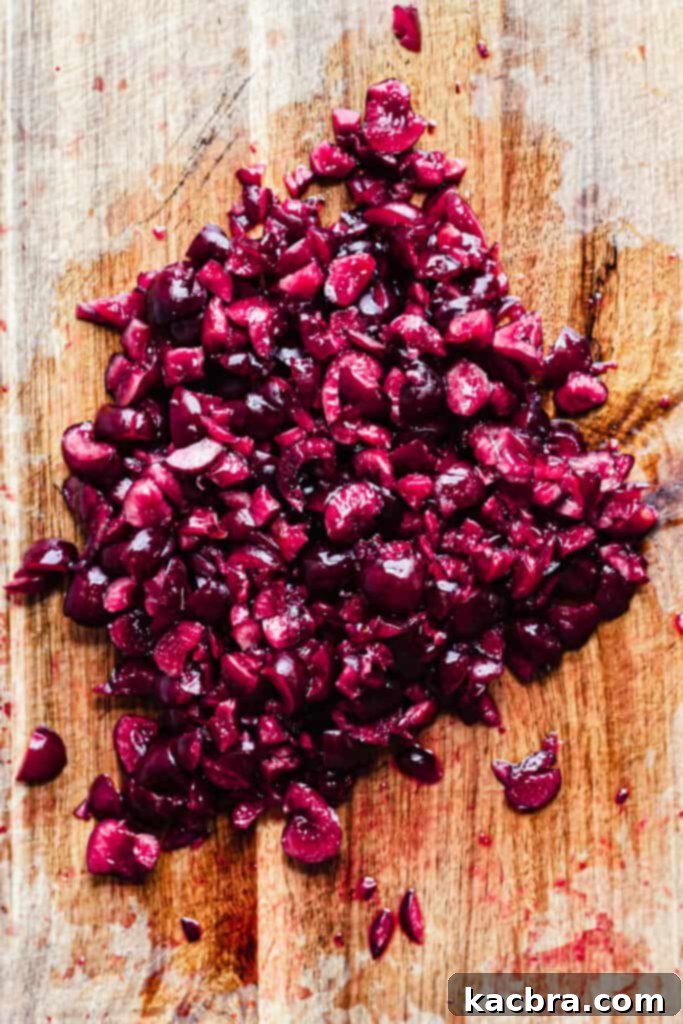 Fresh cherries are being pitted and chopped into a bowl, preparing for the cherry compote layer of the tiramisu.