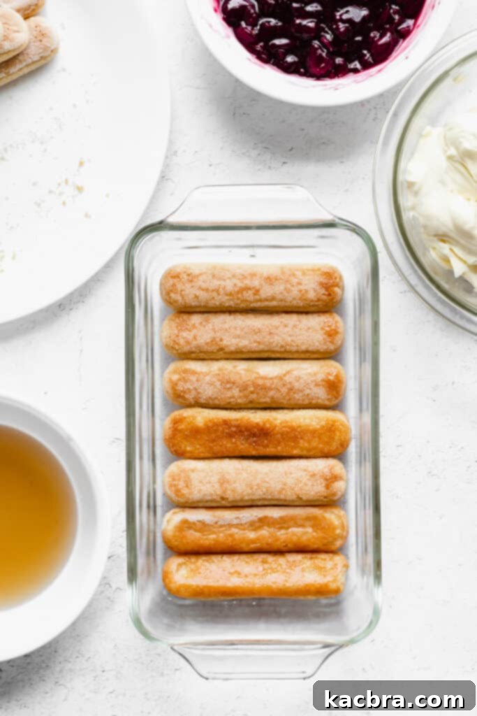 Ladyfingers are quickly dipped into the Amaretto syrup before being arranged in the loaf pan.