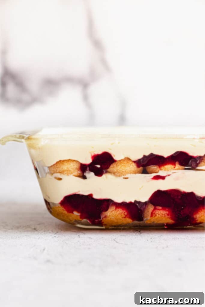 A smooth layer of mascarpone cream is spread over the cherry compote, completing one tier of the tiramisu.