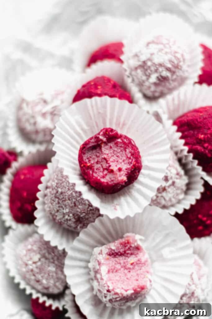 Close up shot of a raspberry brigadeiro with a bite removed, showcasing its fudgy interior and vibrant raspberry coating.