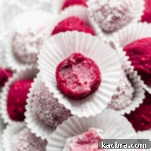 Close up shot of a vibrant raspberry brigadeiro with a small bite removed, showcasing its fudgy texture.