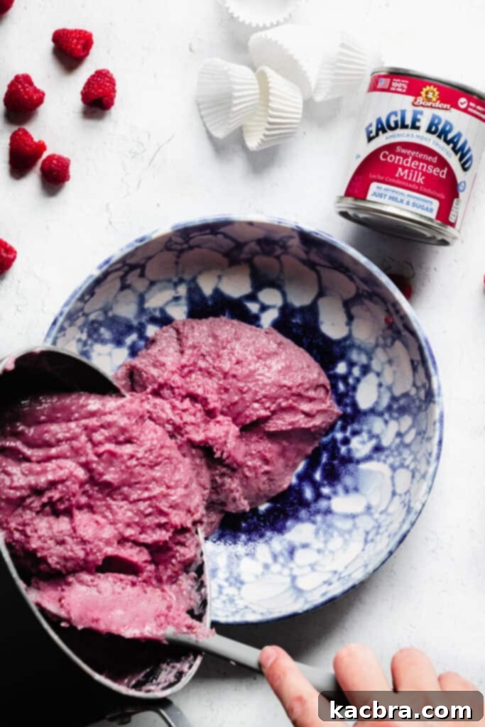Smooth, thick raspberry fudge being poured into a greased shallow bowl, ready for chilling.