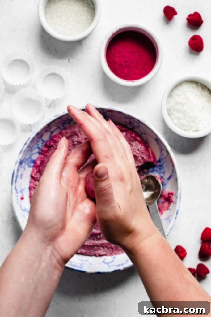 A tablespoon of fudge being skillfully rolled into a smooth ball between two greased hands.