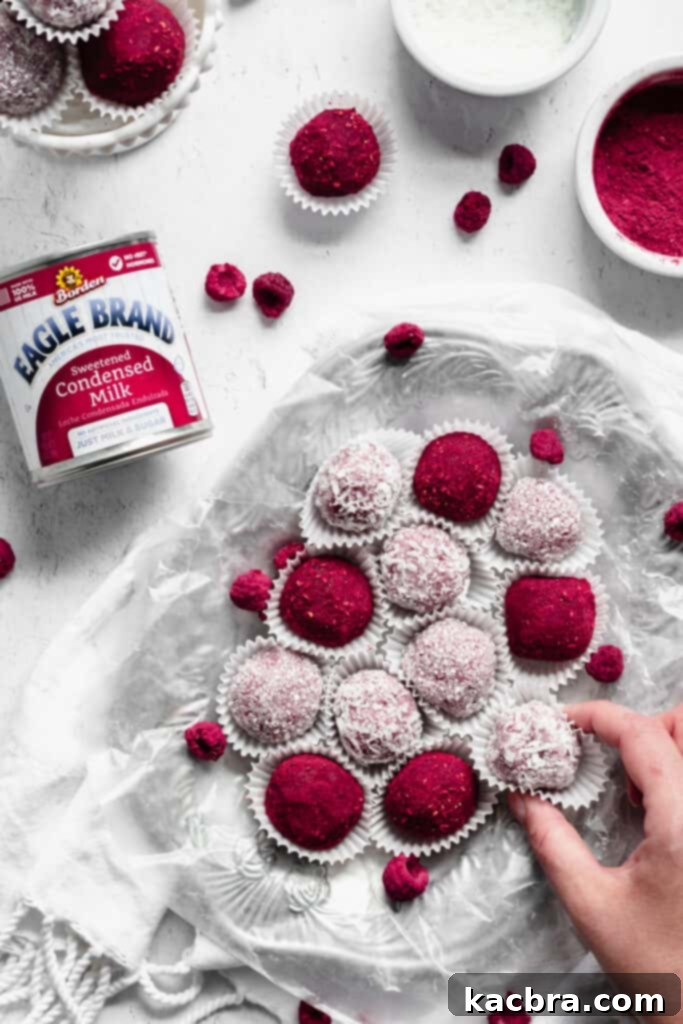 An inviting overhead shot of a platter laden with raspberry brigadeiros, with a hand delicately reaching in to pick up one, emphasizing their irresistible appeal.