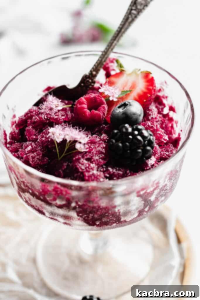 A refreshing Berry Sangria Granita in a glass, garnished with fresh berries.