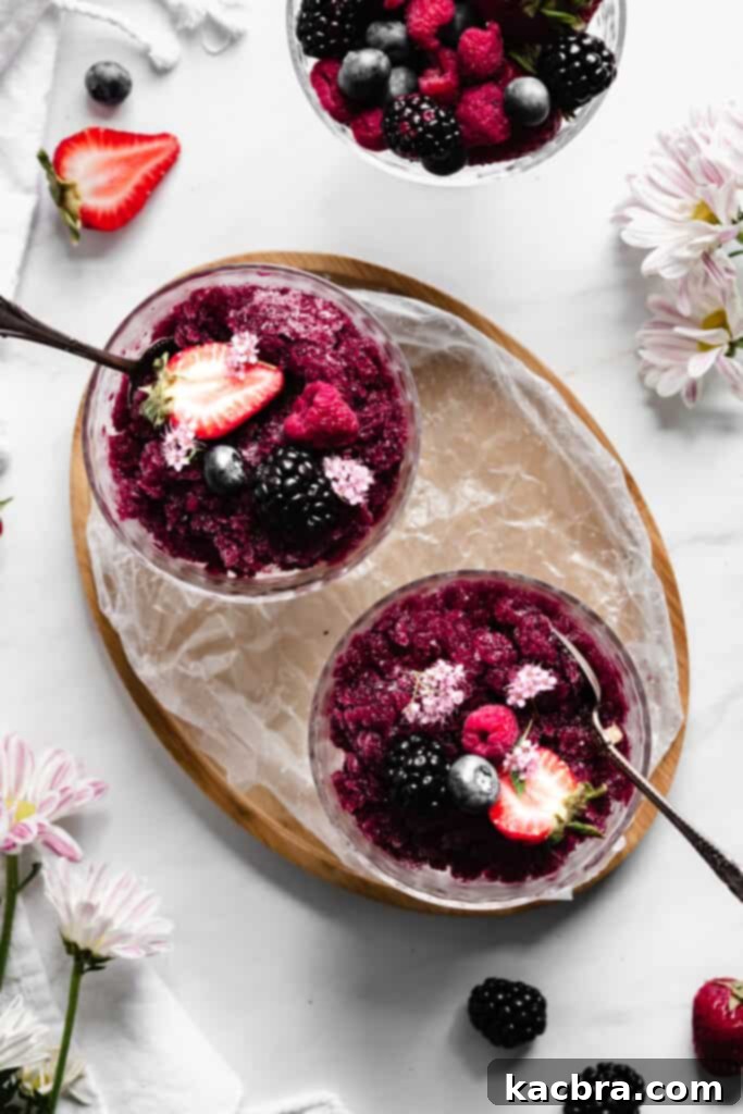 An overhead shot of two coupes with granita and topped with berries. A coupe of berries also sits in the frame.