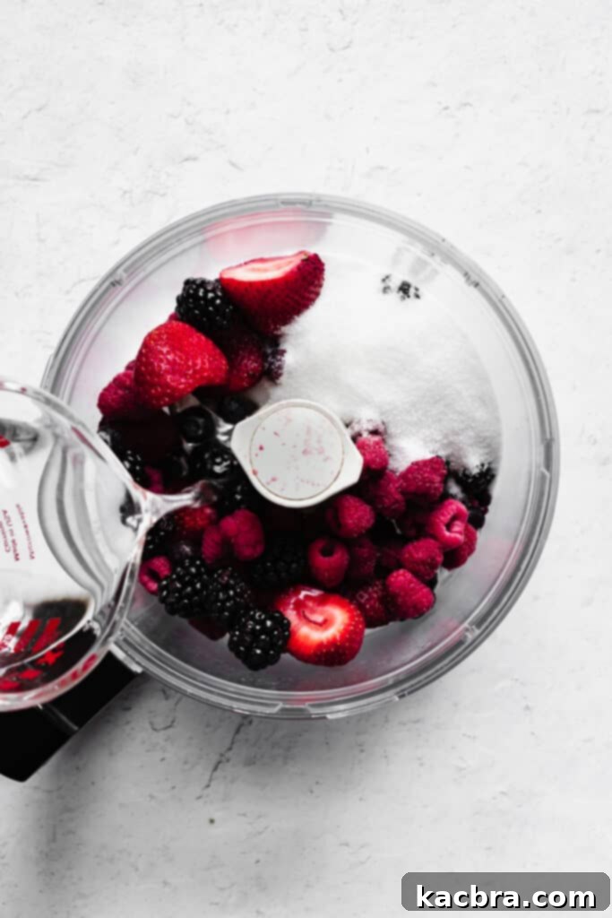 Water is added to a food processor holding mixed berries and sugar.