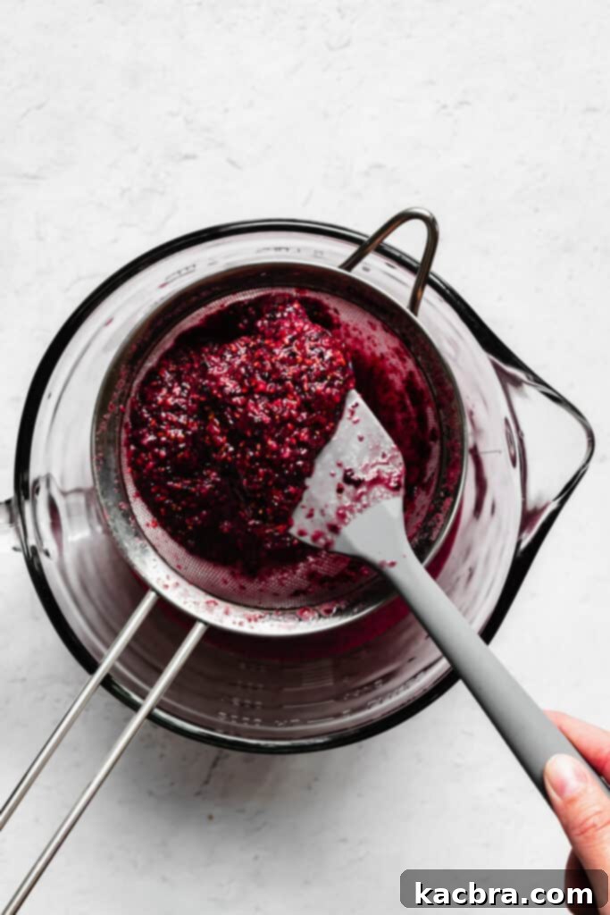 A rubber spatula holds a pile of berry seeds.