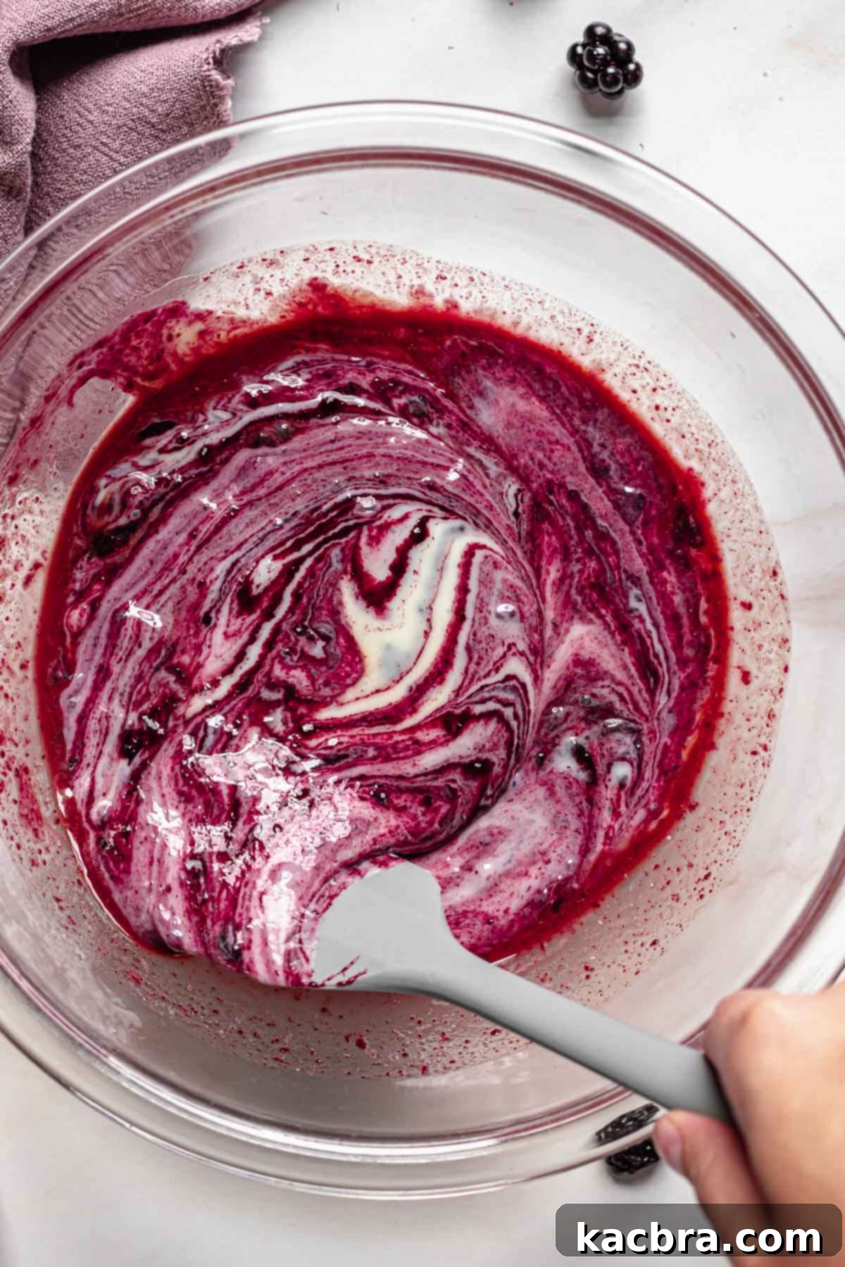 Marbled black raspberry puree folding into sweetened condensed milk.